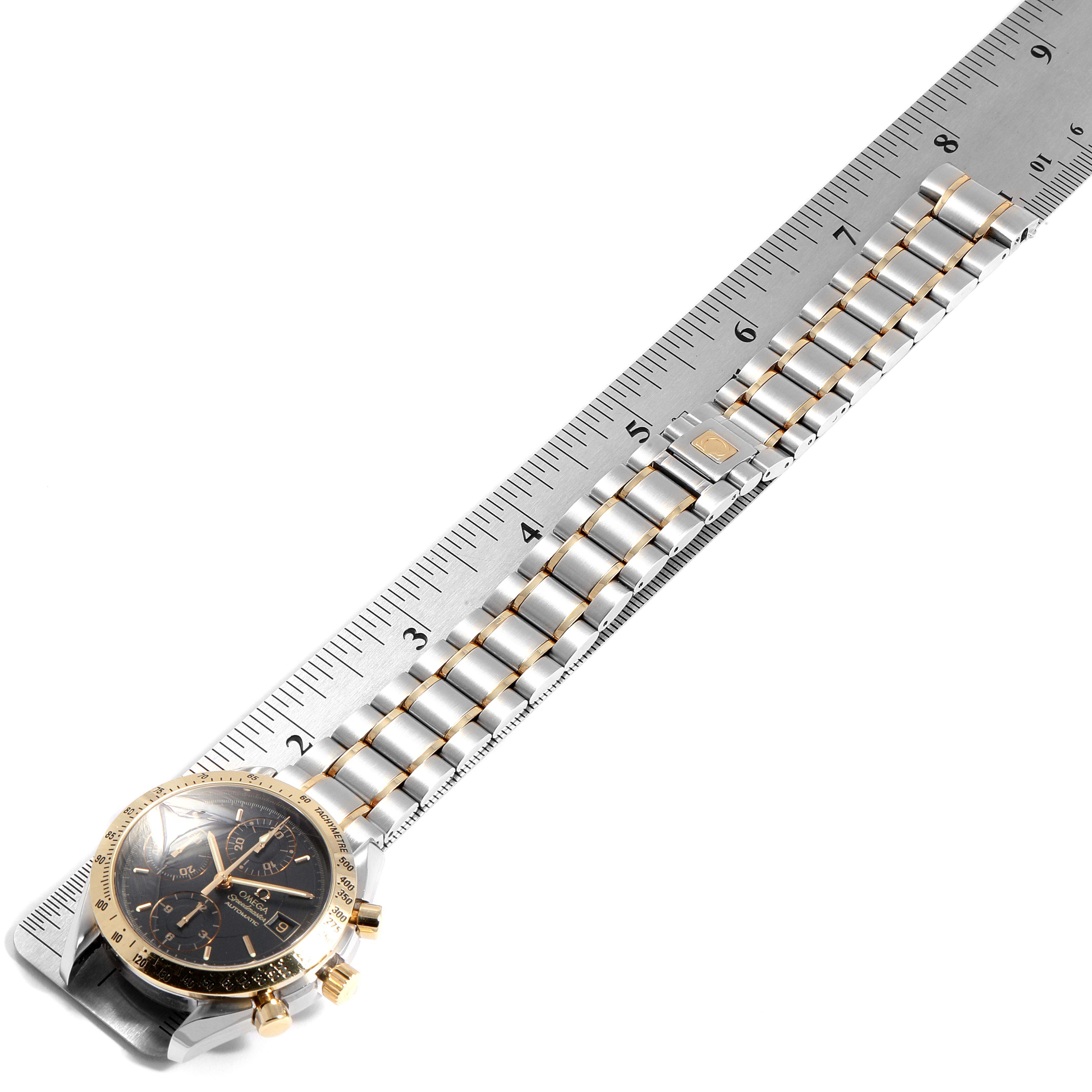 The image shows an Omega Speedmaster 3313.50.00 Men
s Steel and Gold (two tone) Black Dial 3313.50.00 Men
s Steel and Gold (two tone) Black Dial watch lying flat with its bracelet aligned next to a ruler for measurement.