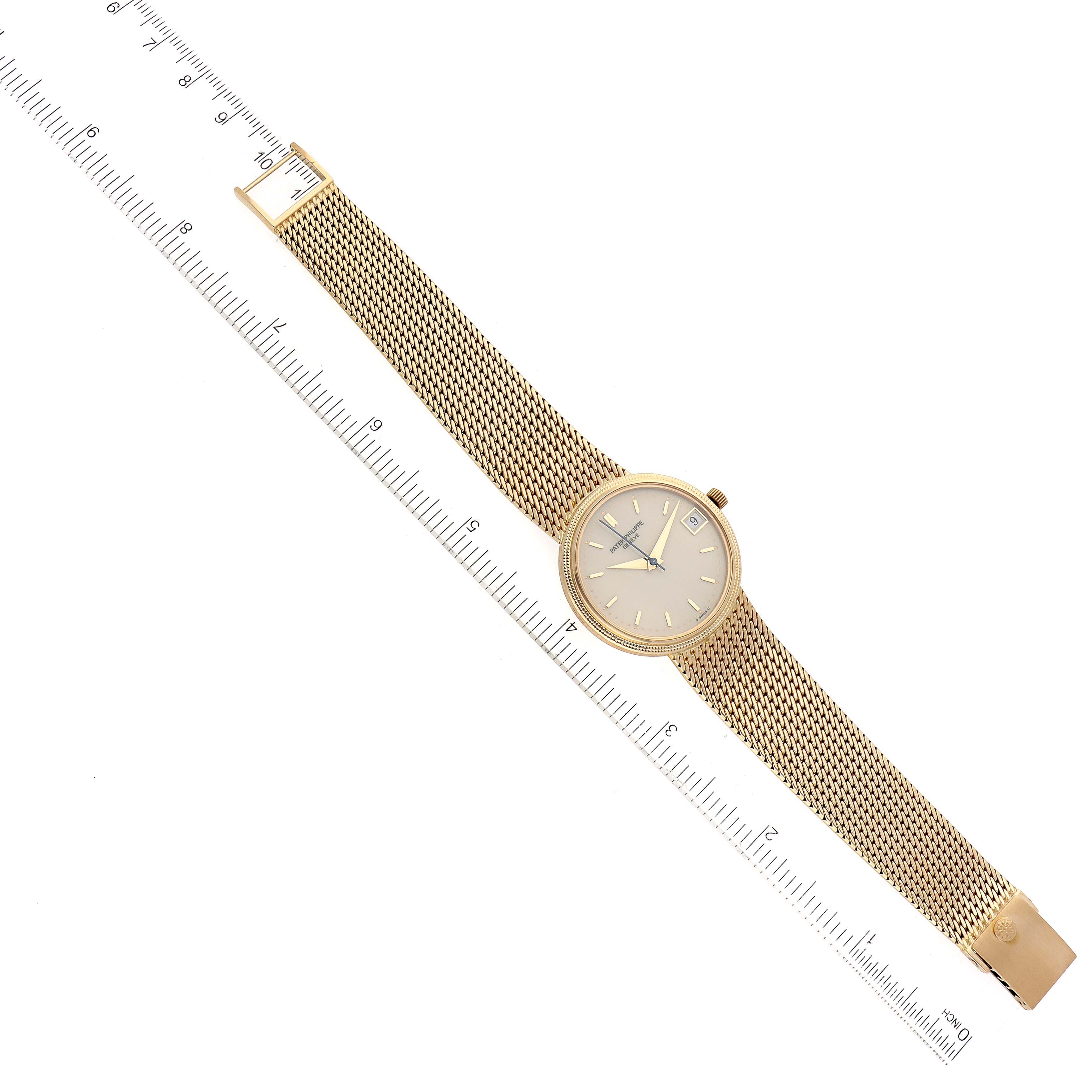 The Patek Philippe Calatrava 3802 Men
s Yellow Gold White Dial 3802 Men
s Yellow Gold White Dial watch is shown from a top-down angle, displaying the full watch including the face, bezel, and metal mesh strap.