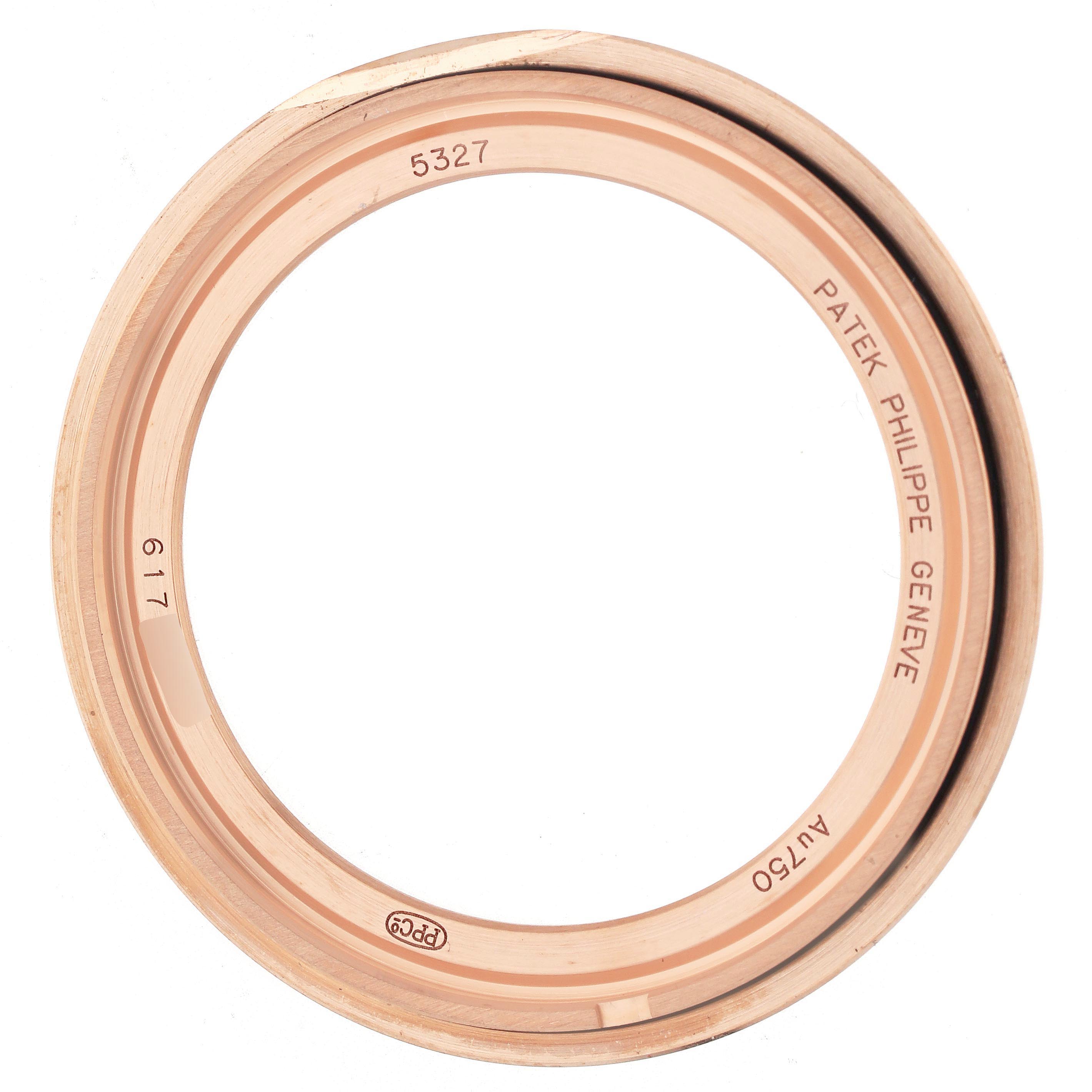 The image shows a Patek Philippe Complications 5327R Men
s Rose Gold Beige Dial 5327R Men
s Rose Gold Beige Dial watch bezel, viewed from the top, featuring engravings and markings.