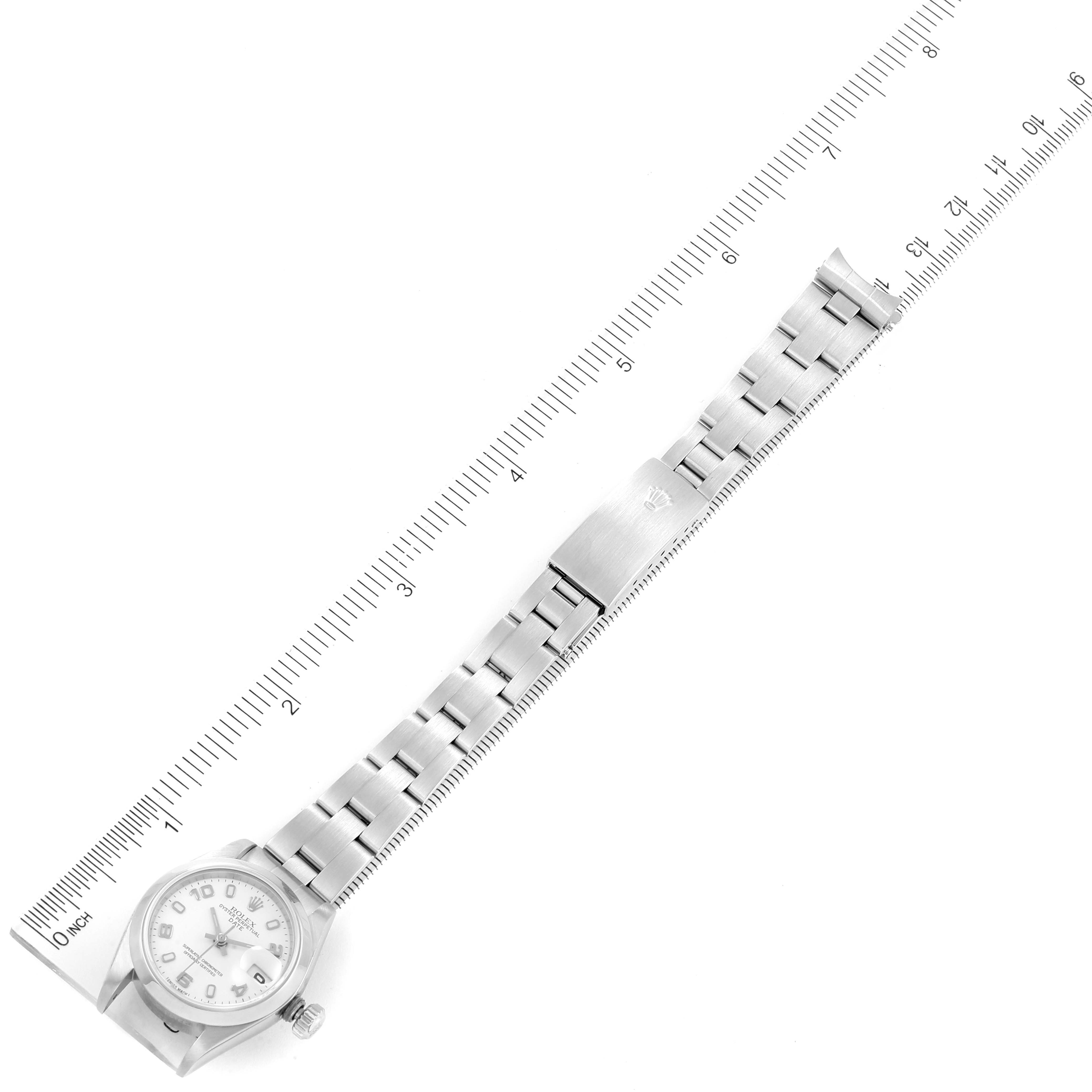 The image shows a top-down view of a Rolex Date 79160 Women
s Stainless Steel White Dial 79160 Women
s Stainless Steel White Dial model watch with a metal bracelet alongside a ruler for scale.