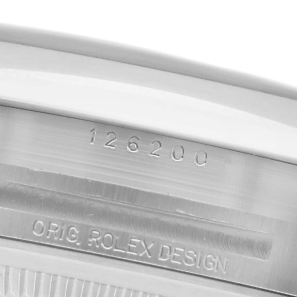 The image shows a close-up of the engravings on the side of the Rolex Datejust 126200 Men
s Stainless Steel Blue Dial 126200 Men
s Stainless Steel Blue Dial model, highlighting the serial number and "ORIG. ROLEX DESIGN."