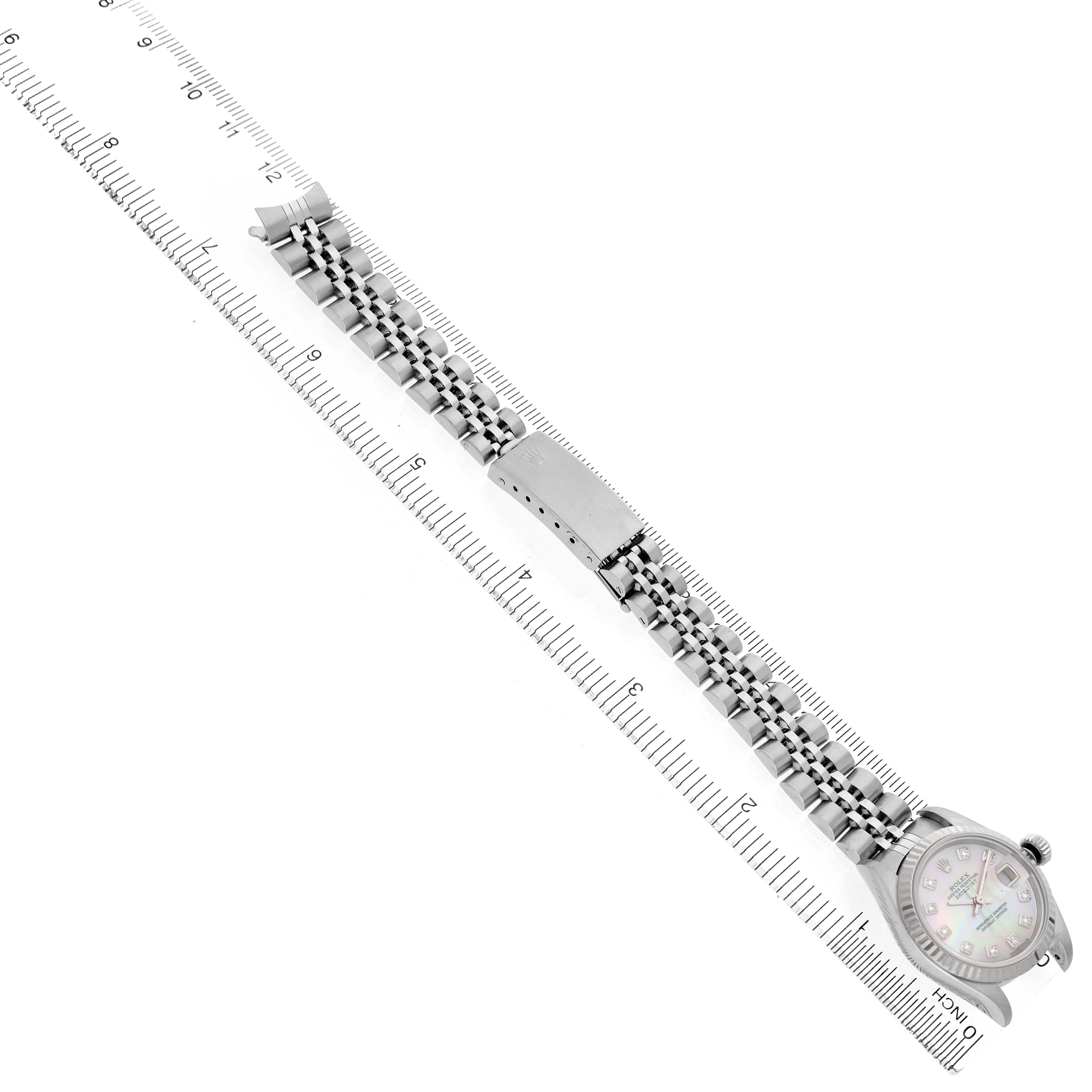 The Rolex Datejust 79174 Women's Stainless Steel Mother of Pearl Dial watch is shown laid flat with its bracelet aligned with a ruler for measurement.