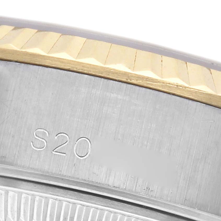 The image shows a close-up of the Rolex Datejust 69173 Women
s Steel and Gold (two tone) Champagne Dial 69173 Women
s Steel and Gold (two tone) Champagne Dial
s fluted bezel and part of the casing with an engraved serial number.