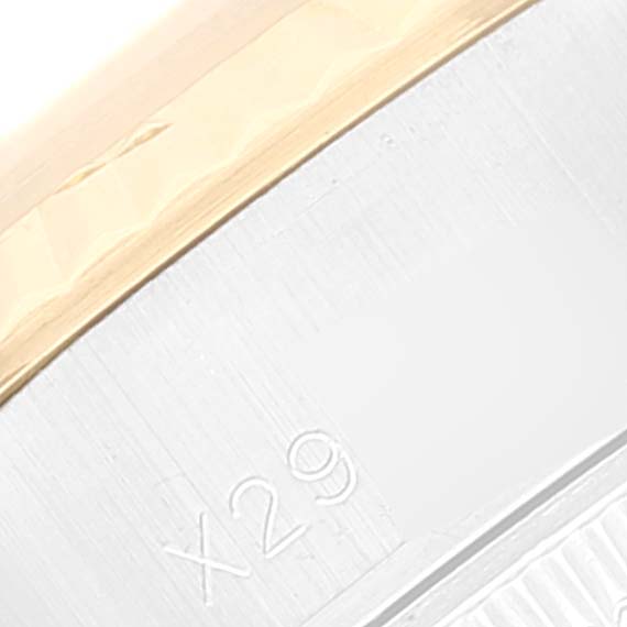 This close-up image of a Rolex Datejust 69173 Women's Steel and Gold (two tone) Beige Dial 69173 Women's Steel and Gold (two tone) Beige Dial watch shows a part of the bezel and case, along with the engraving "X29".