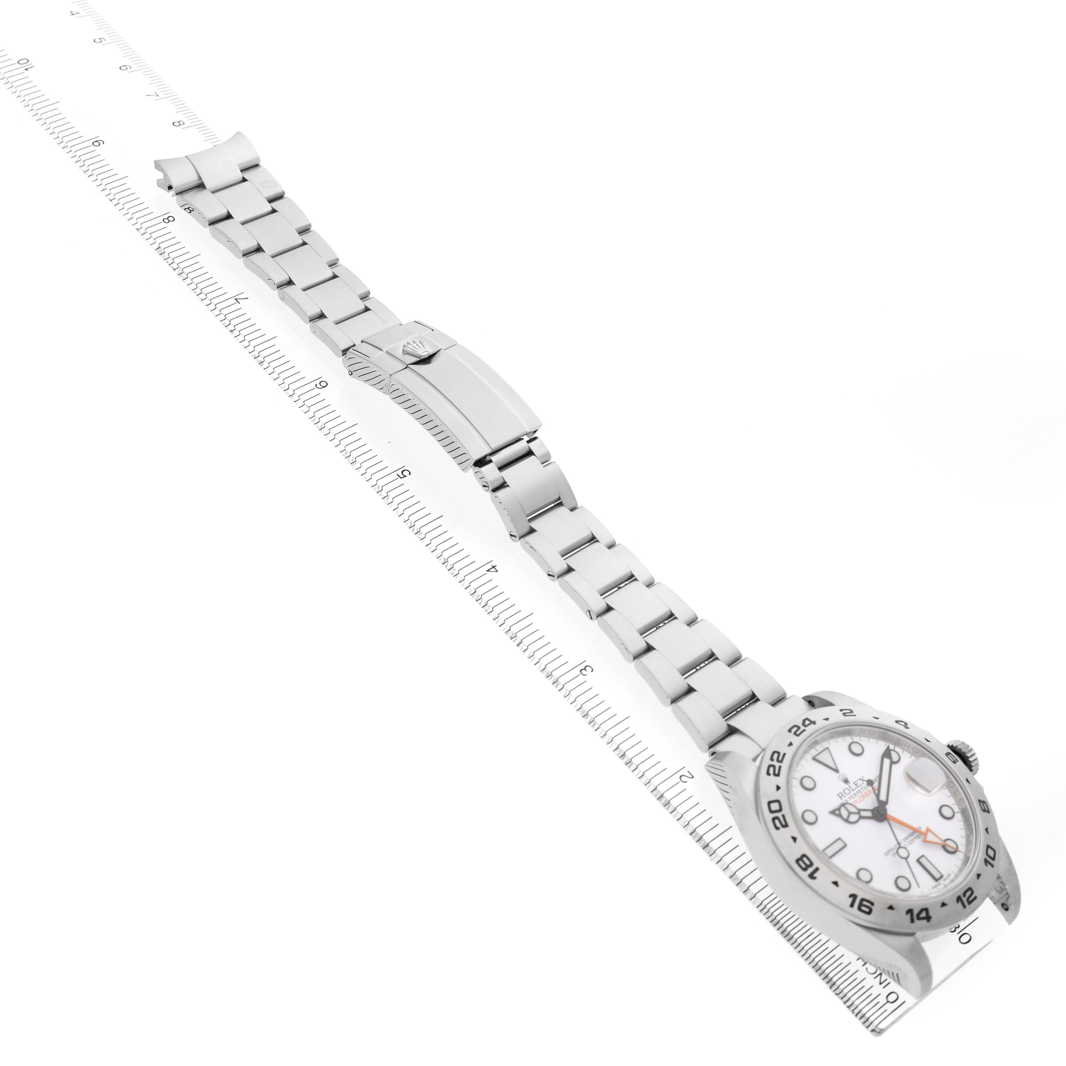 The image shows a Rolex Explorer 216570 Men's Stainless Steel White Dial watch from a top view, displaying the face, bracelet, and clasp laid out against a ruler.