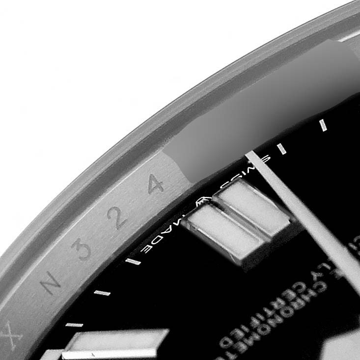 The image shows a close-up of the dial and hands of a Rolex Oyster Perpetual 124300 Men's Stainless Steel Black Dial watch, focusing on the hour indexes and bezel.