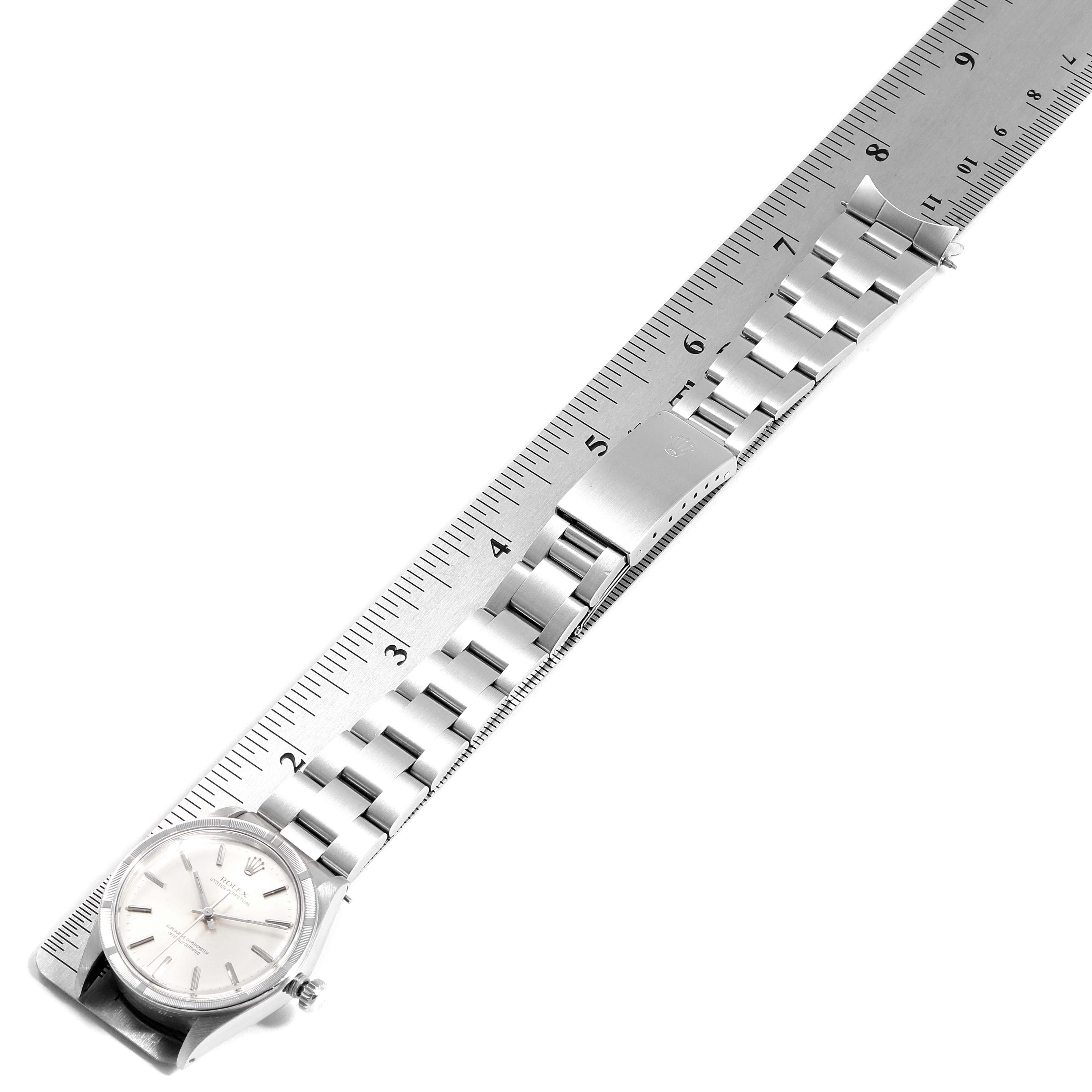 The Vintage Collection Rolex watch is shown flat, showcasing its face, links, and clasp on a measuring scale.