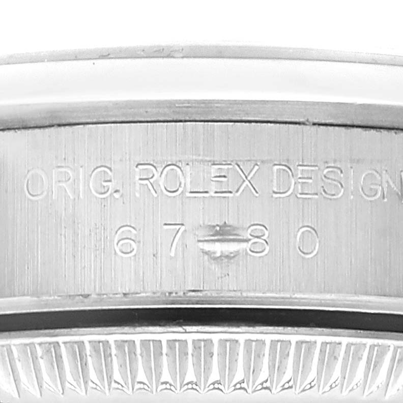 This image shows a close-up of the edge of a Rolex Oyster Perpetual 67180 Women's Stainless Steel Black Dial 67180 Women's Stainless Steel Black Dial watch case with engraved text and model number.