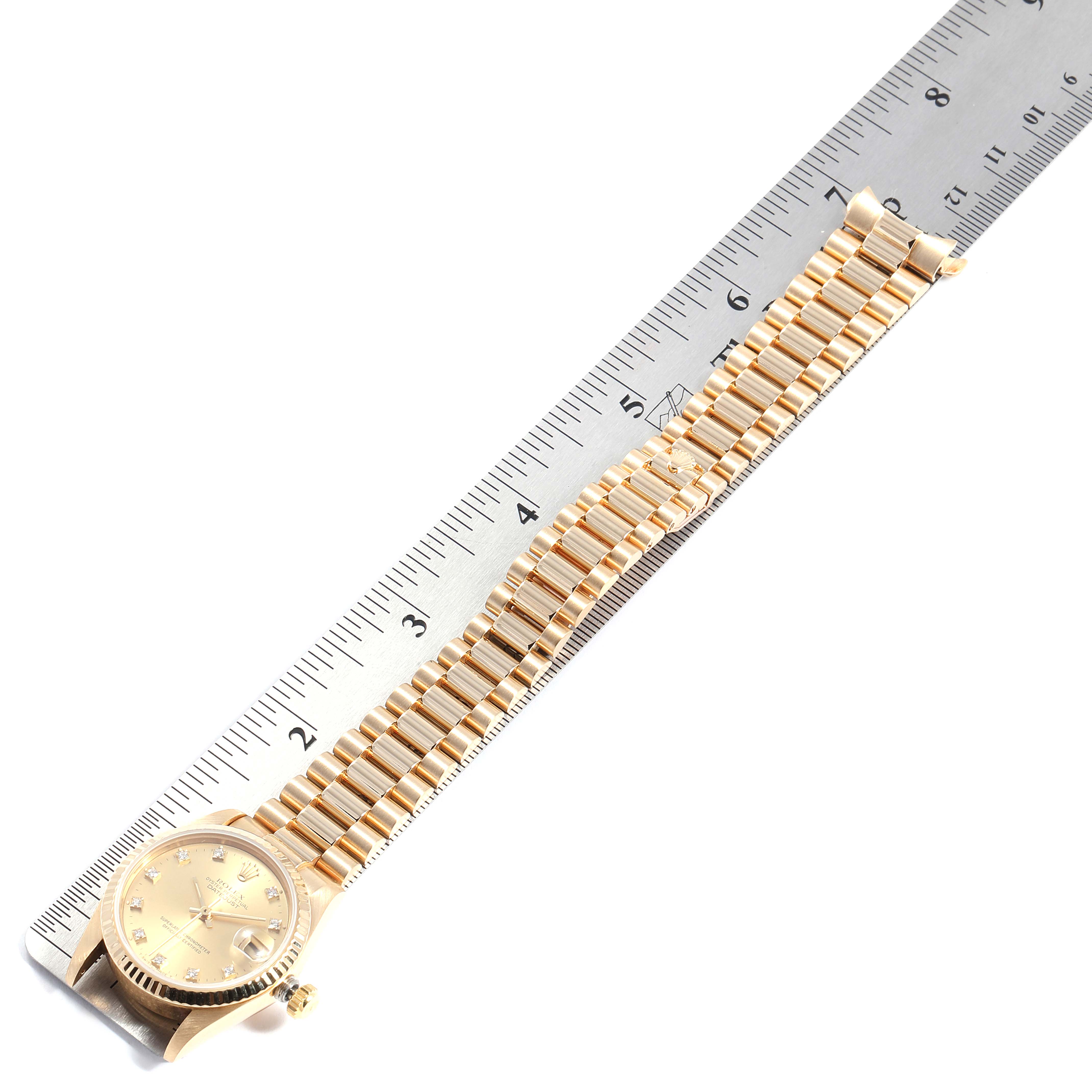 The image shows a Rolex President 68278 Women
s Yellow Gold Champagne Dial 68278 Women
s Yellow Gold Champagne Dial model watch, displayed face-up, with its band stretched out alongside a ruler.