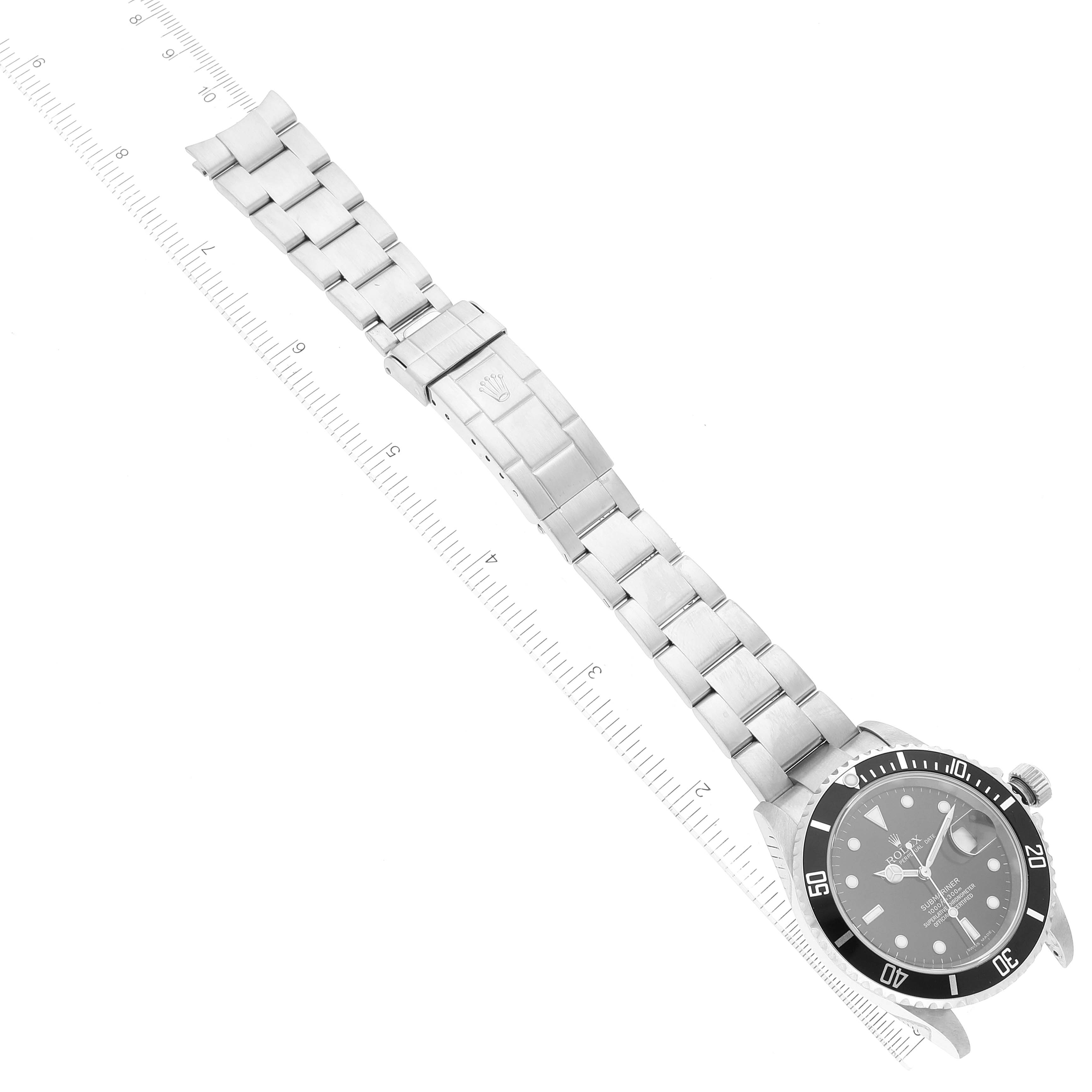 The image shows a top-down view of a Rolex Submariner 16610 Men's Stainless Steel Black Dial 16610 Men's Stainless Steel Black Dial watch, displaying the face, bezel, and full bracelet with a measuring ruler alongside.