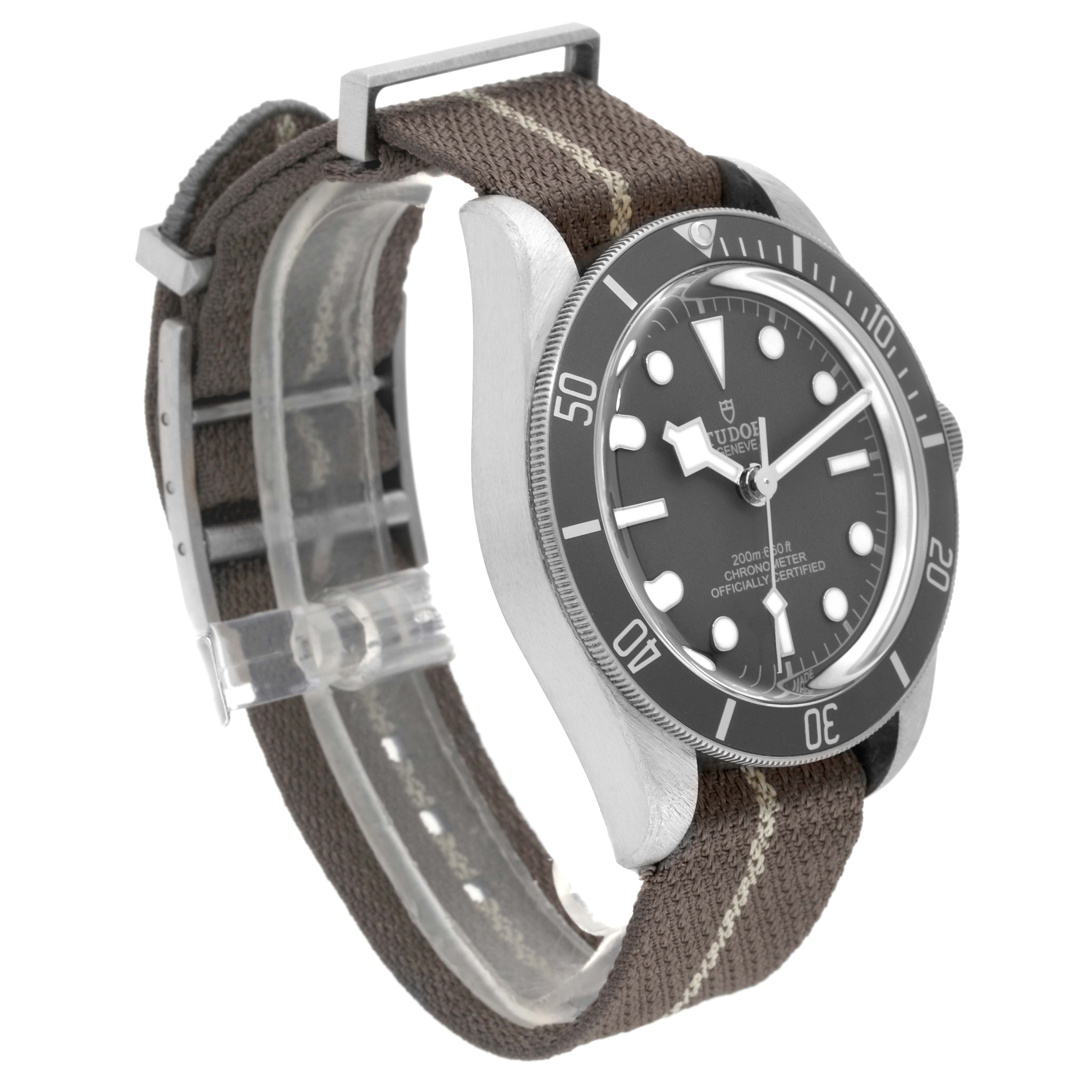 The image shows a side angle of the Tudor Heritage Black Bay 79010SG Men
s Stainless Steel Grey Dial 79010SG Men
s Stainless Steel Grey Dial watch, highlighting the dial, bezel, and fabric strap.