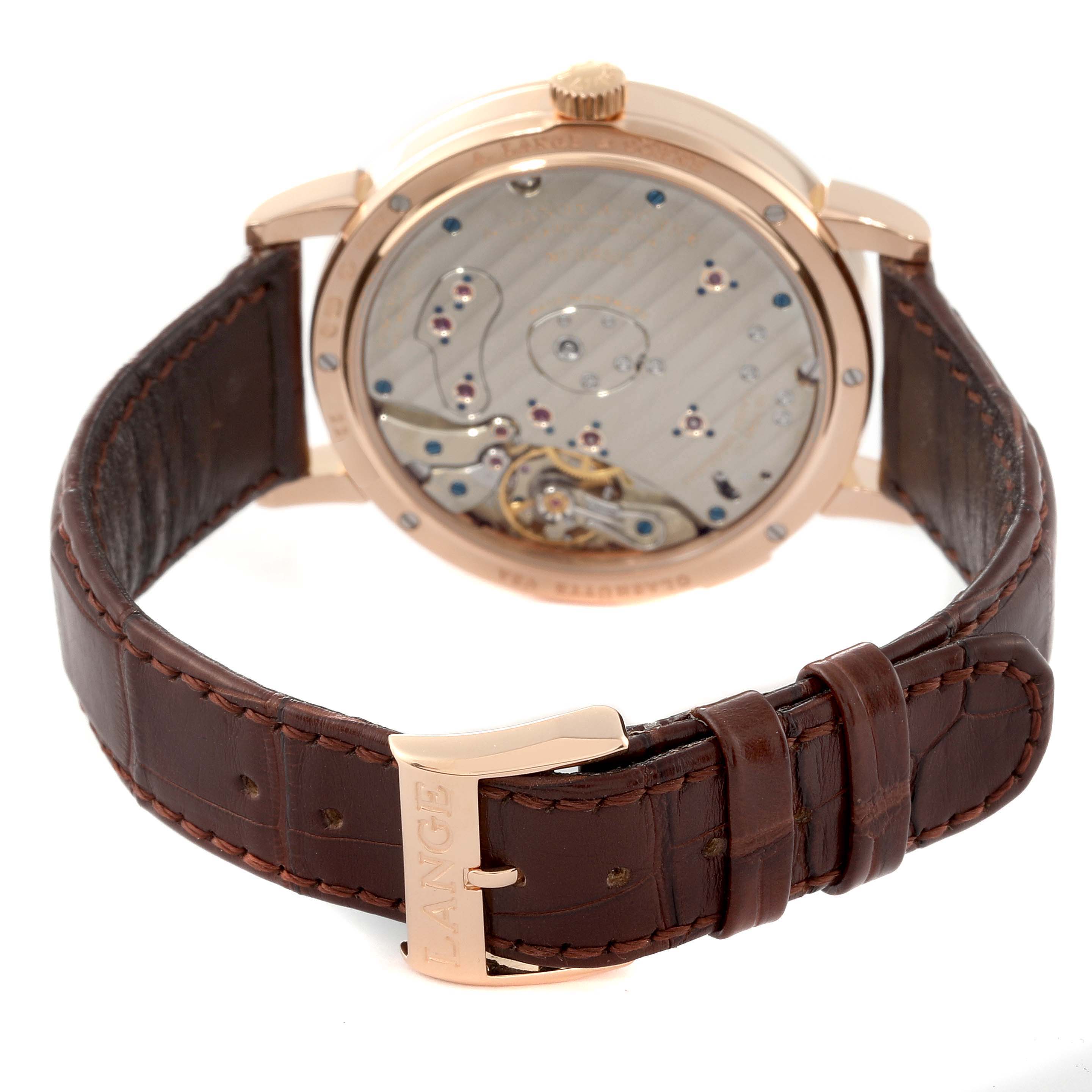 The image shows the back view and clasp of the A. Lange & Sohne Lange 1 139.032 Men's Rose Gold Silver Dial watch, revealing parts of its movement and brown leather strap.