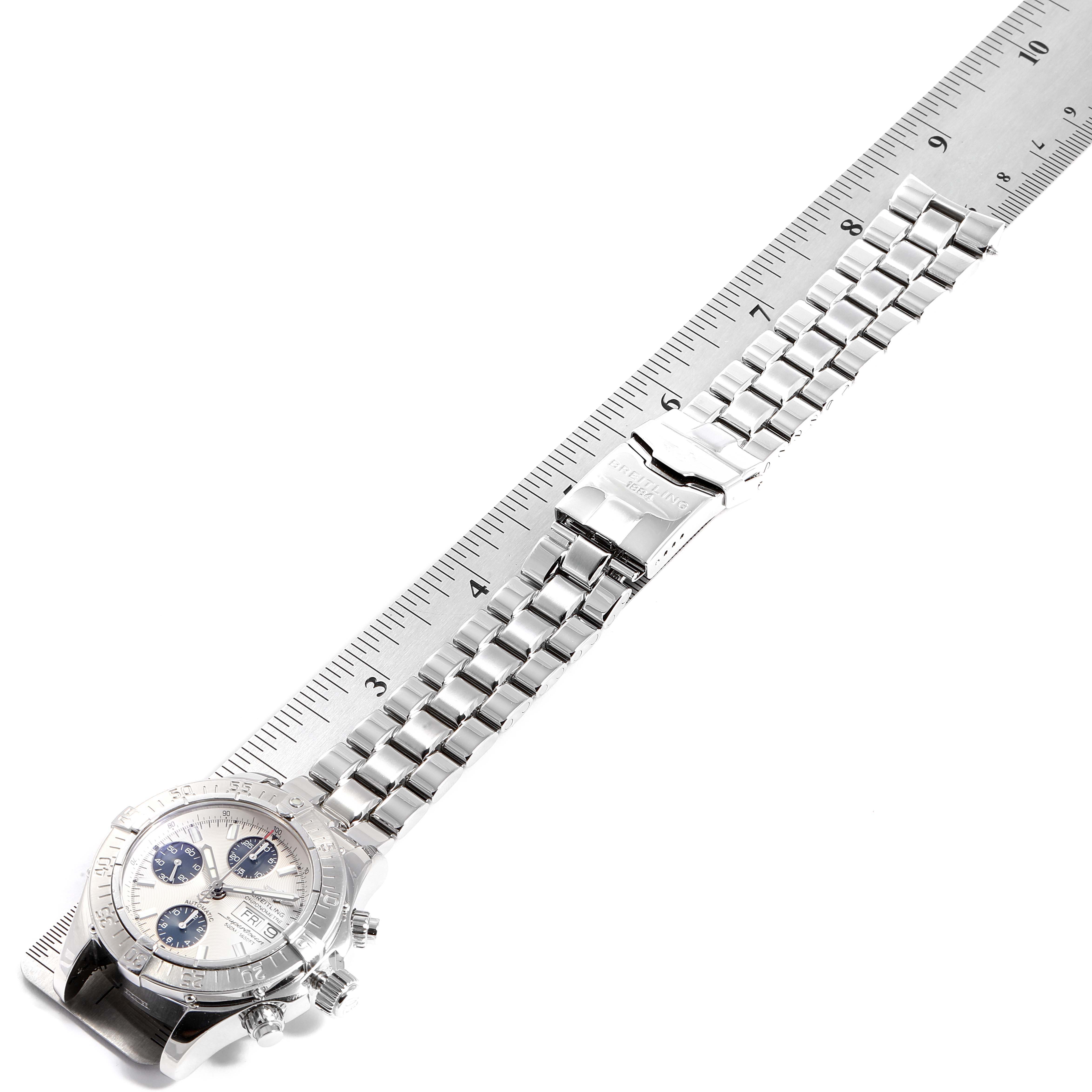 The image shows Breitling's Superocean watch laid flat, highlighting its bracelet and clasp alongside a ruler for scale.