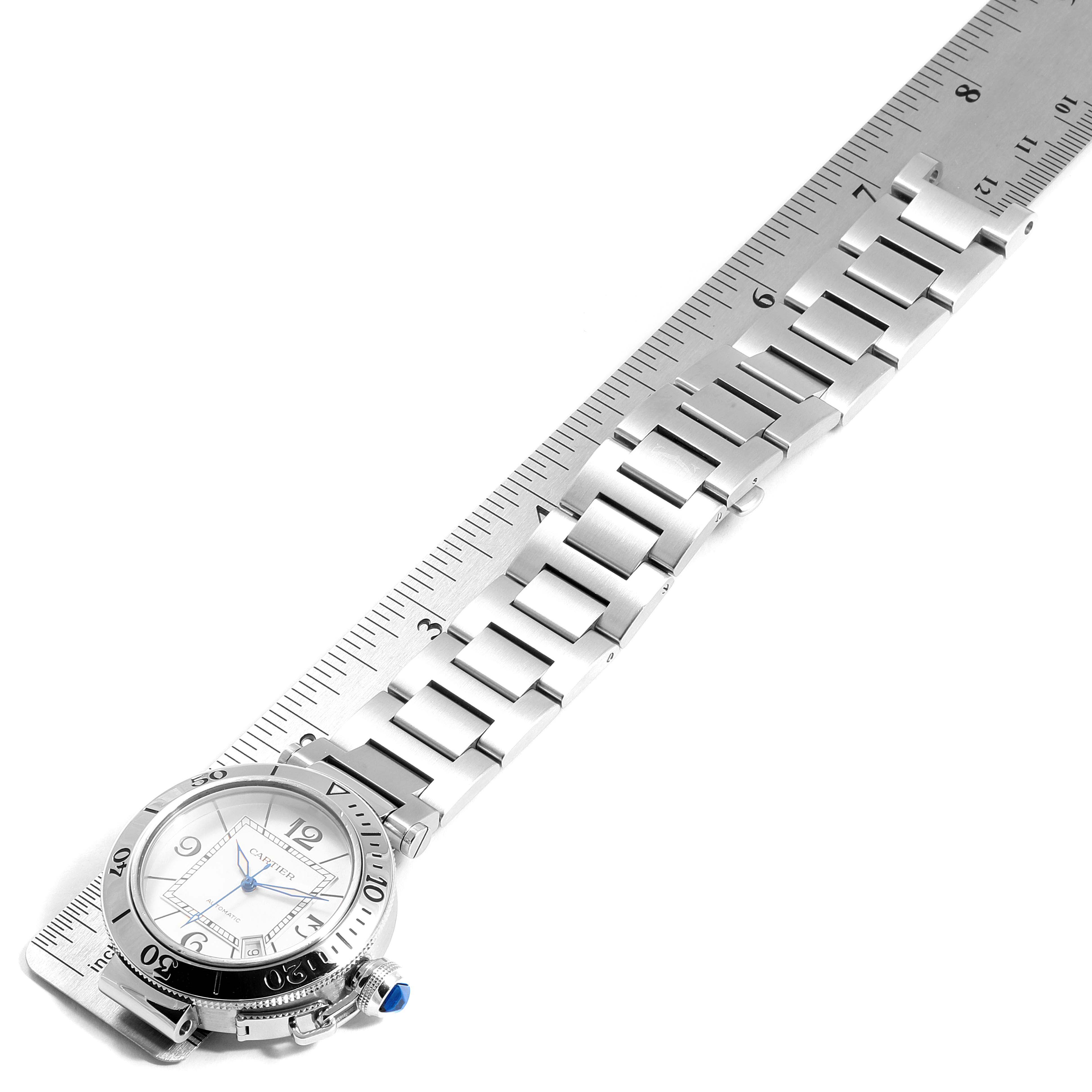 The image shows a Cartier Pasha W31080M7 Men's Stainless Steel Silver Dial W31080M7 Men's Stainless Steel Silver Dial watch at an angle highlighting its face, bezel, and steel bracelet, with a ruler for measurement.