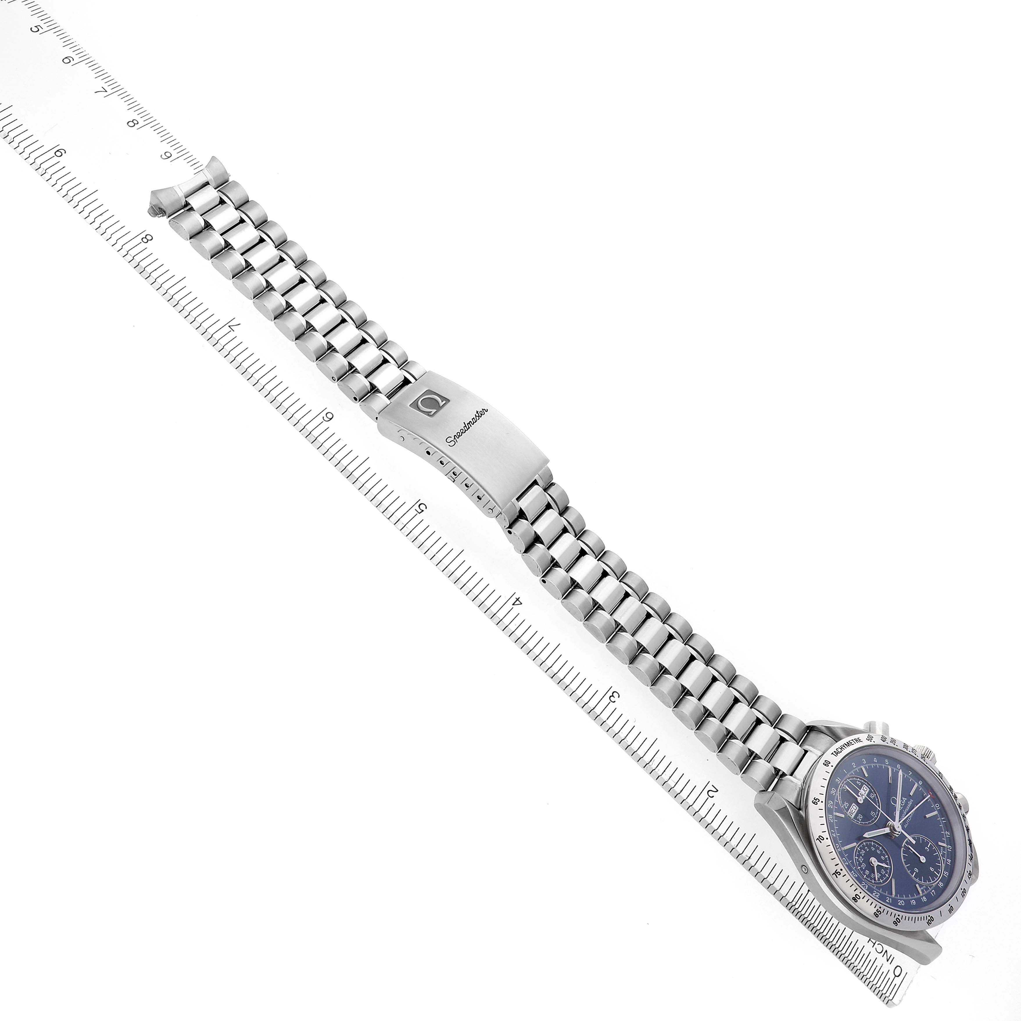 The Omega Speedmaster 3521.80.00 Men
s Stainless Steel Blue Dial 3521.80.00 Men
s Stainless Steel Blue Dial watch is shown at an angle displaying its bracelet laid flat with the clasp open, alongside a ruler for scale.