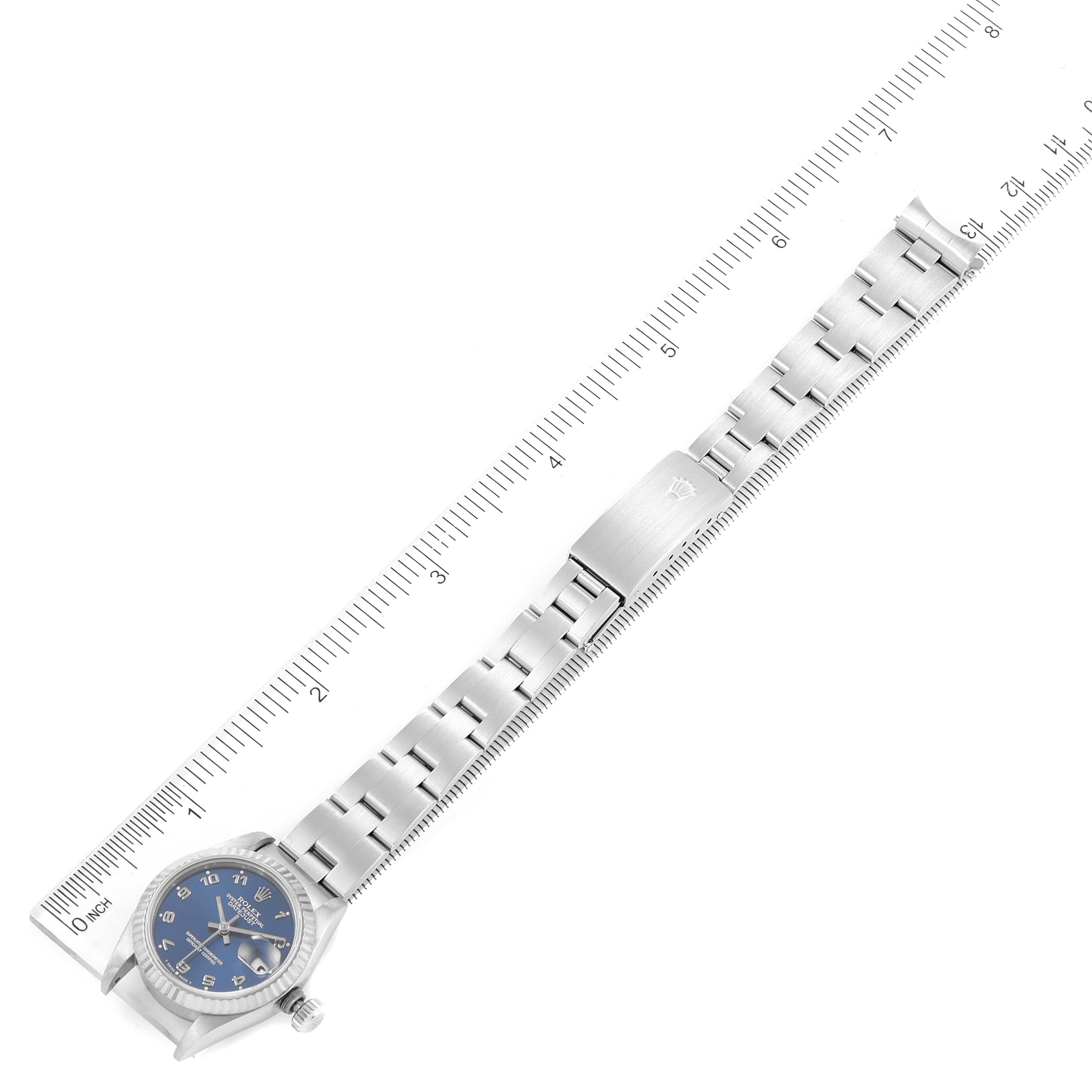The image shows a Rolex Datejust 69174 Women
s Stainless Steel Blue Dial 69174 Women
s Stainless Steel Blue Dial watch laid flat with a ruler beside it to measure the length of the band.