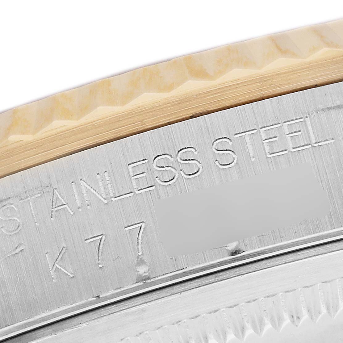 This close-up image shows the side of the stainless steel bezel of a Rolex Datejust 16233 Men's Steel and Gold (two tone) Black Dial 16233 Men's Steel and Gold (two tone) Black Dial watch, highlighting engraved text.