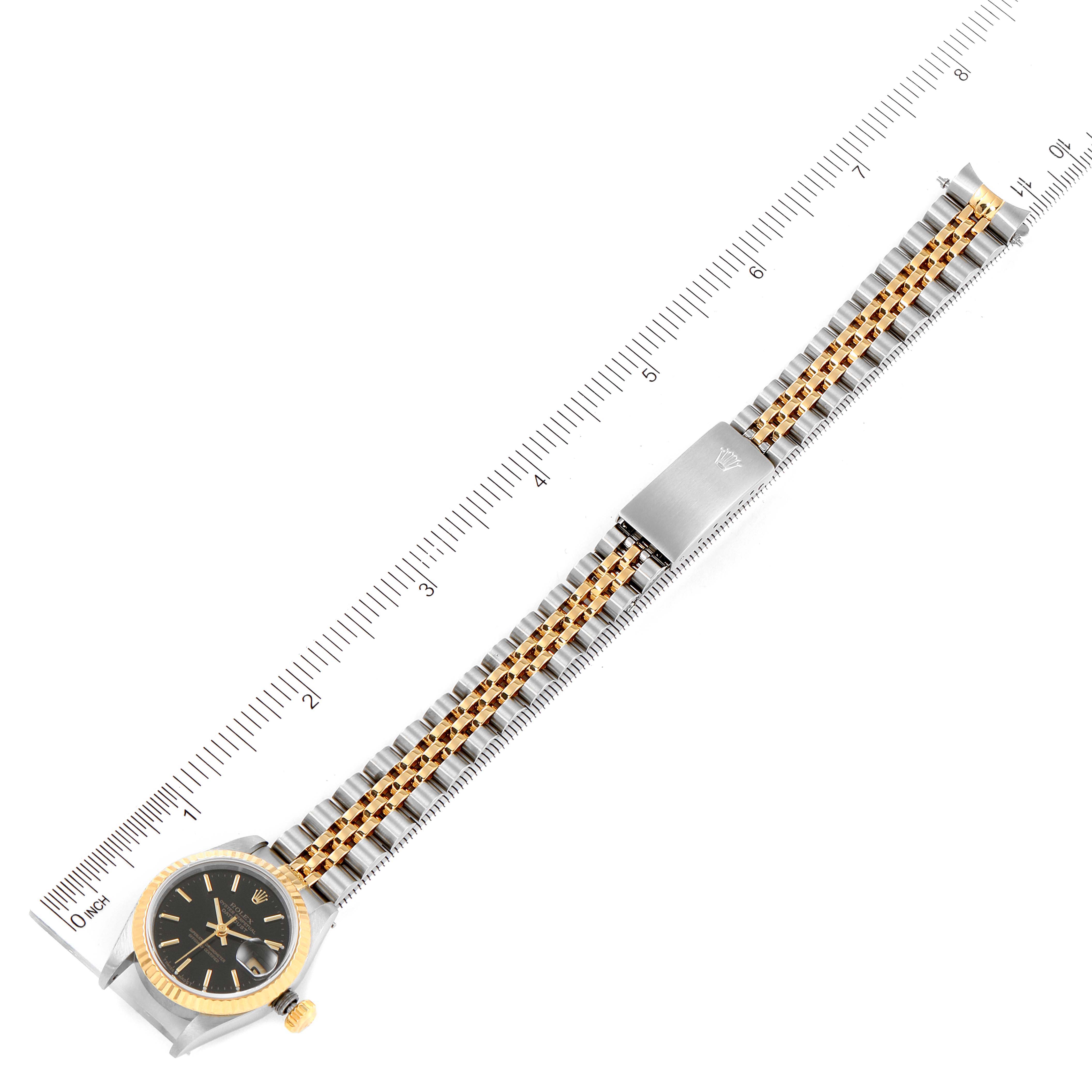 The image shows a top view of a Rolex Datejust 69173 Women's Stainless Steel Black Dial 69173 Women's Stainless Steel Black Dial watch with its band and clasp, placed alongside a ruler for scale.