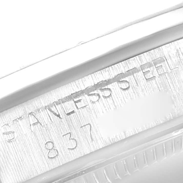 The image shows the side engraving on a Rolex Mid-Size 67480 Women's Stainless Steel Silver Dial 67480 Women's Stainless Steel Silver Dial watch indicating "STAINLESS STEEL" and part of a serial number.