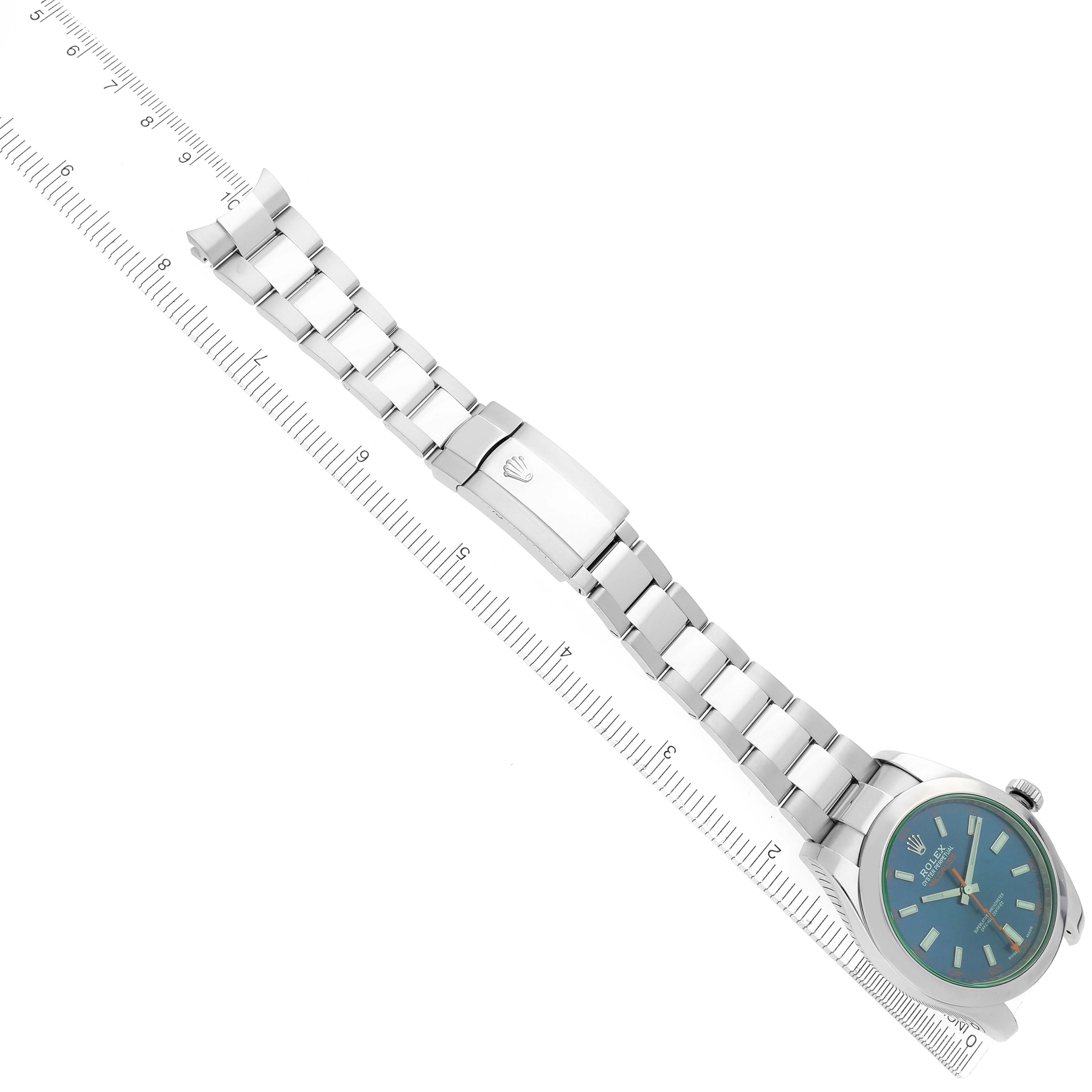 The Rolex Milgauss 116400GV Men
s Stainless Steel Blue Dial 116400GV Men
s Stainless Steel Blue Dial watch is shown from an angled top view, displaying the face, bracelet, and clasp on a ruler background.