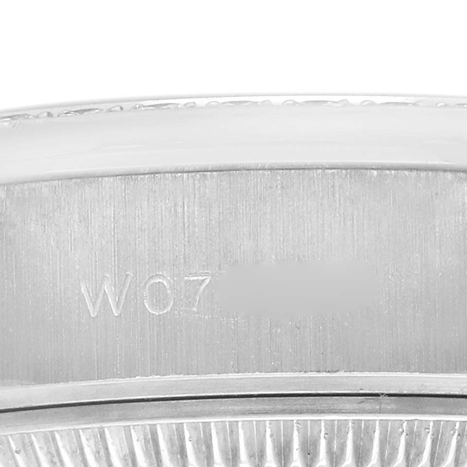 The image shows a close-up of the side of the Rolex President 69136 Women
s Platinum Silver Dial 69136 Women
s Platinum Silver Dial watch, focusing on its serial engraving.