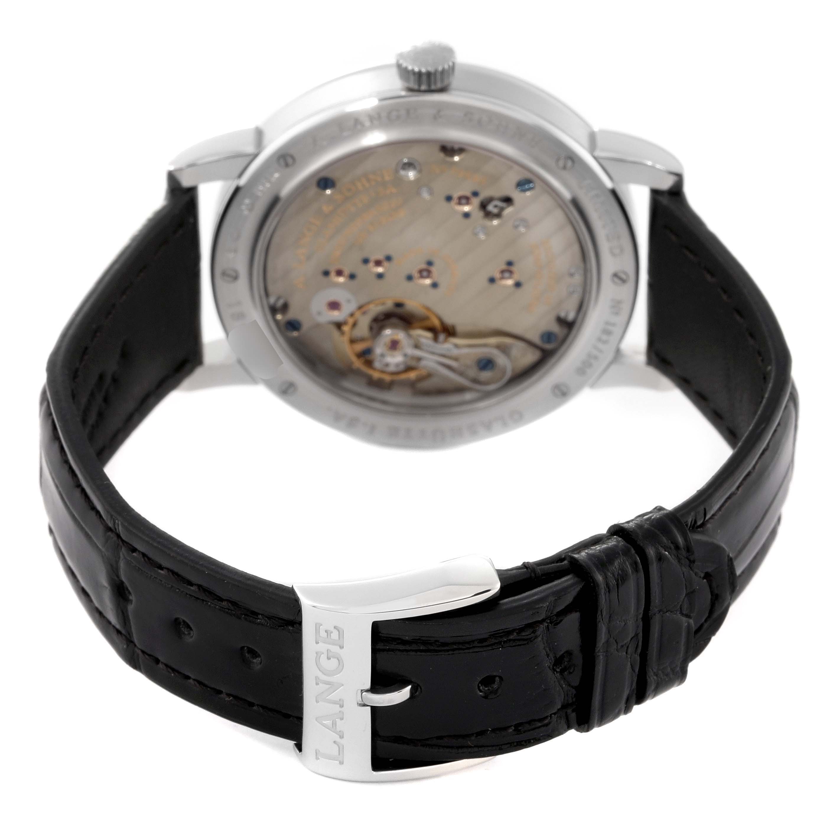 The image shows the back view of the A. Lange & Sohne 1815 233.025 Men's Platinum Silver Dial model watch, highlighting its movement and black leather strap with the clasp.