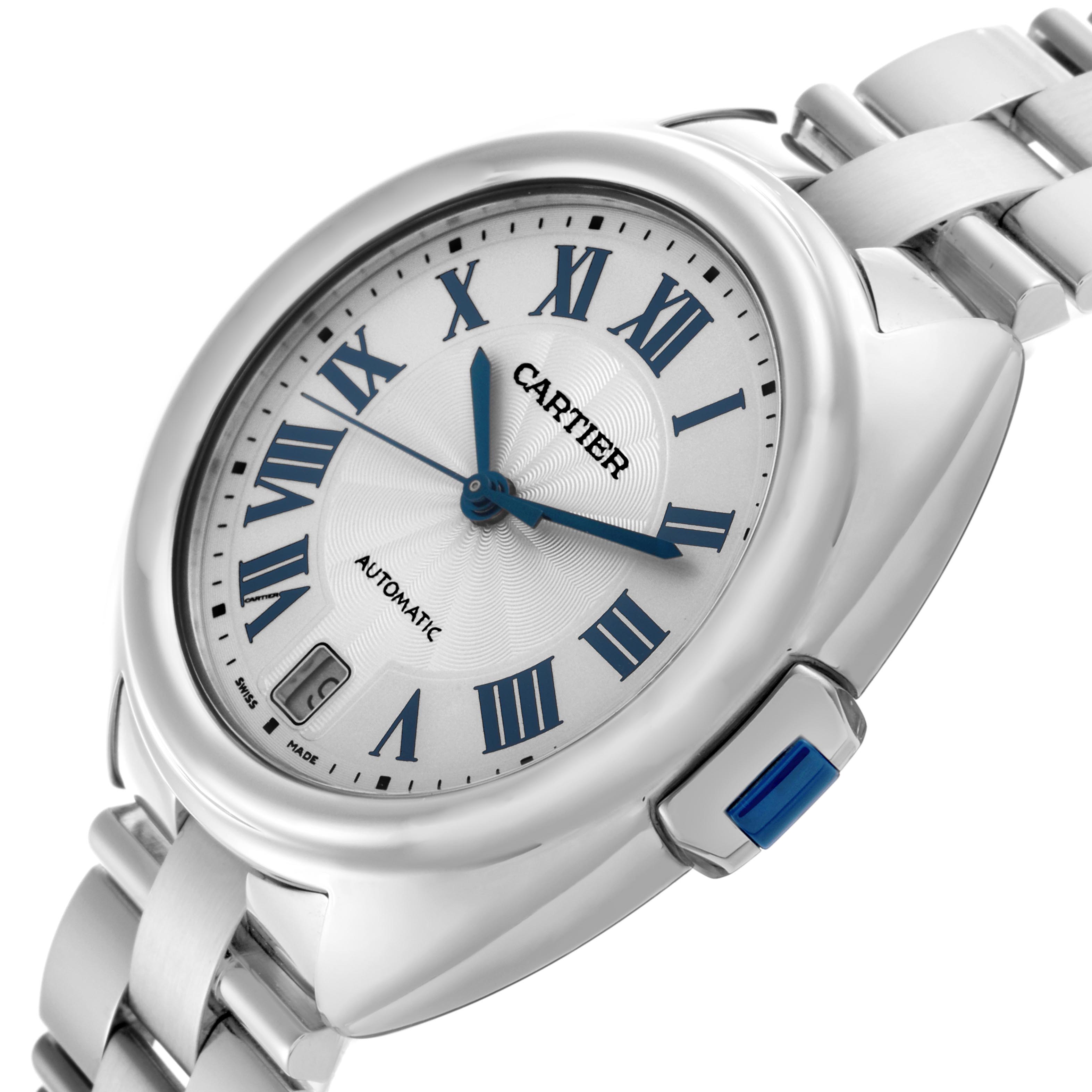 The Cartier Clé watch is shown at a slight angle, highlighting the dial, blue hands, crown, and part of the bracelet.