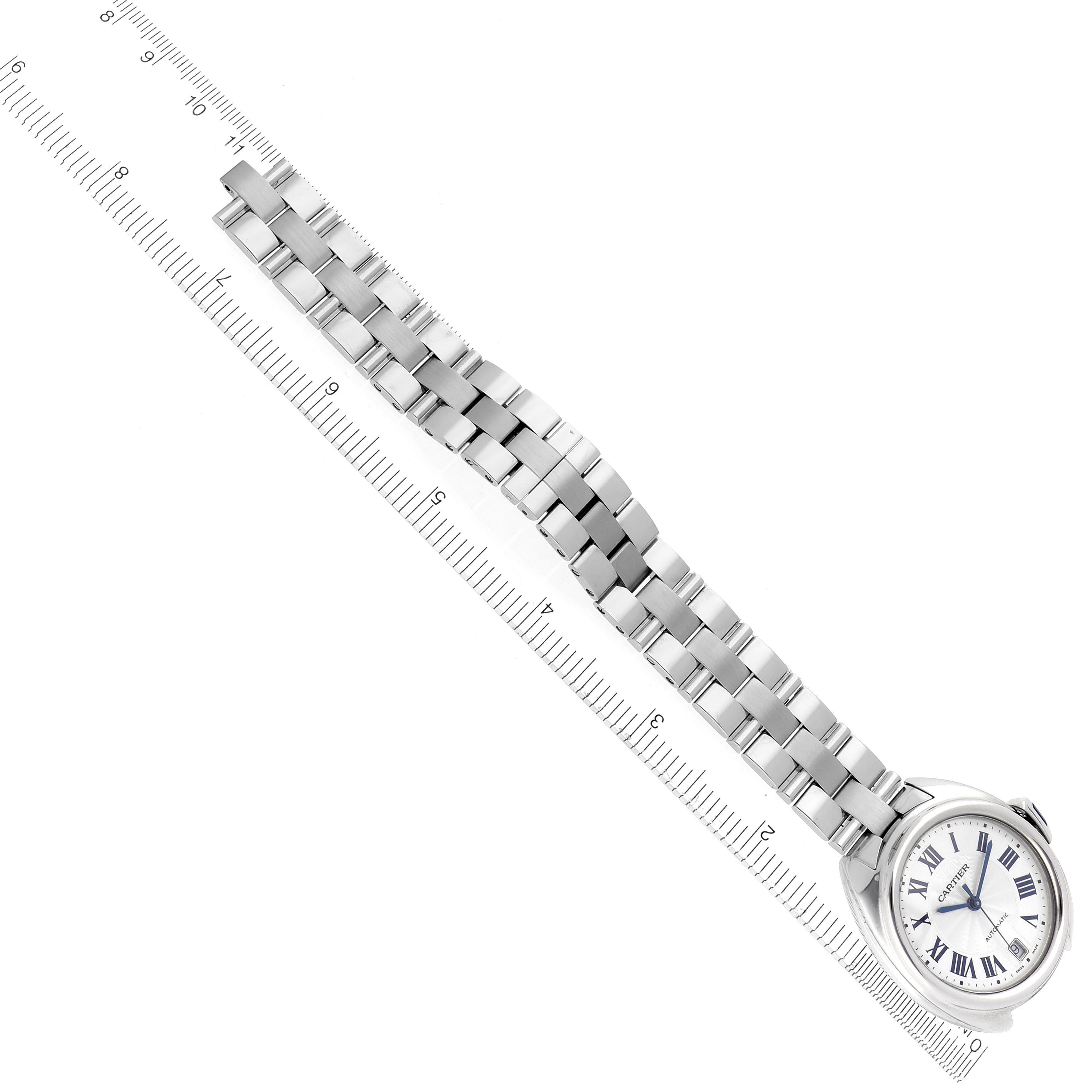 The Cartier Clé watch is displayed diagonally with its stainless steel bracelet fully extended alongside a ruler.