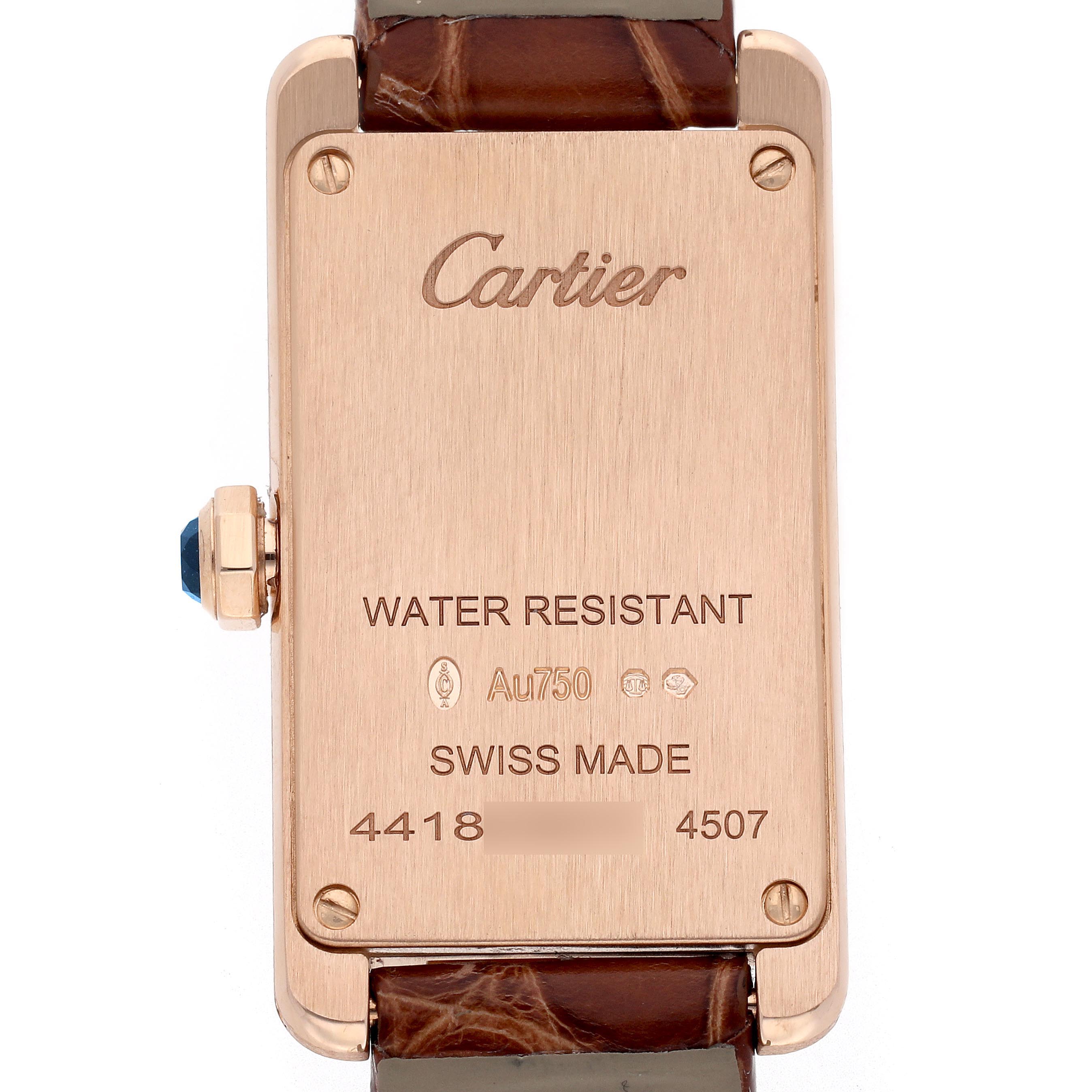 The image shows the back case of the Cartier Tank Americaine W2607456 Women
s Rose Gold Silver Dial W2607456 Women
s Rose Gold Silver Dial watch with engravings and a glimpse of the strap.