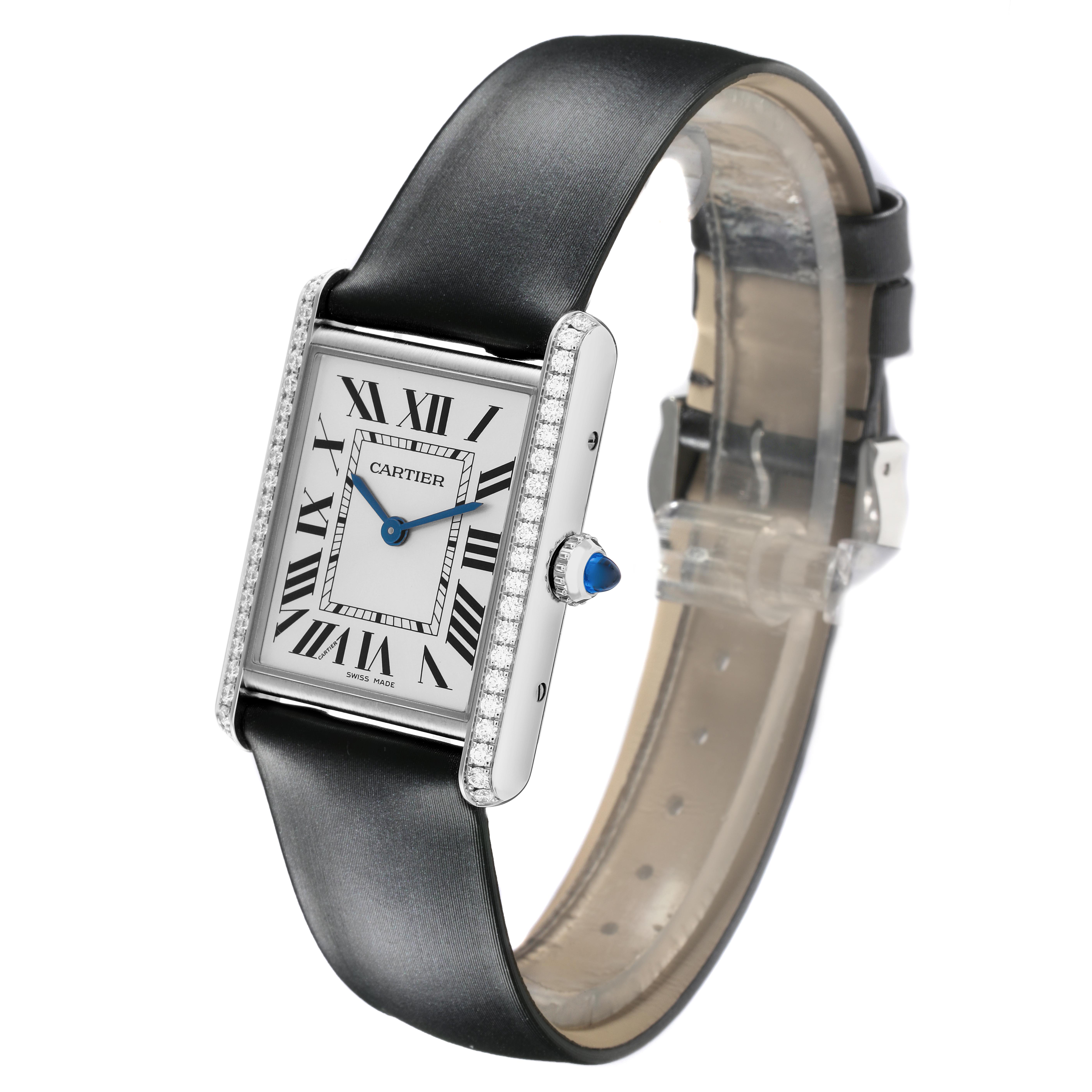 The Cartier Tank Must W4TA0017 Women
s Stainless Steel Silver Dial W4TA0017 Women
s Stainless Steel Silver Dial watch is shown at a three-quarter angle, highlighting its face, Roman numerals, leather strap, and bejeweled crown.