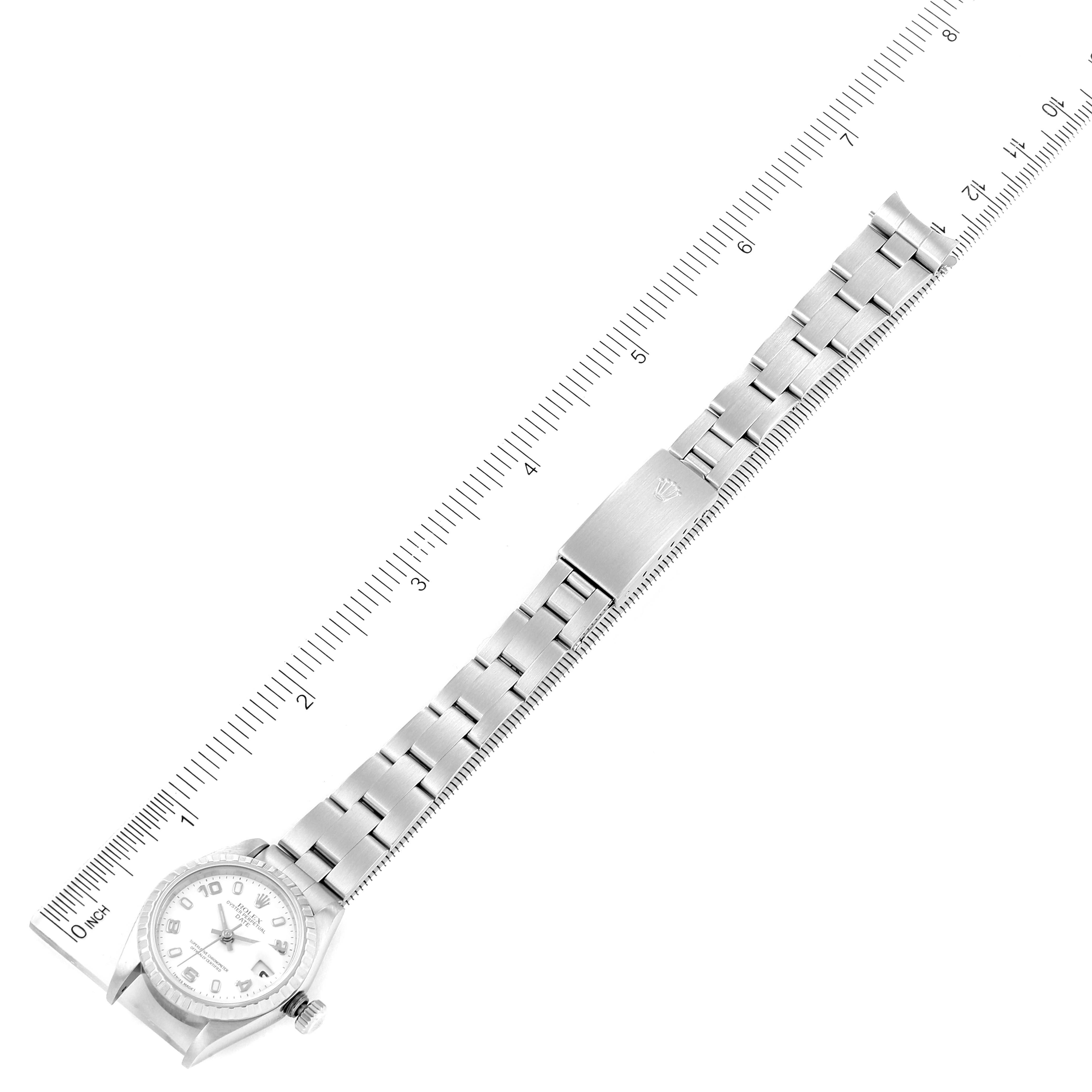 The image shows an overhead view of a Rolex Date 79240 Women
s Stainless Steel White Dial 79240 Women
s Stainless Steel White Dial model watch with its full bracelet laid out alongside a ruler.