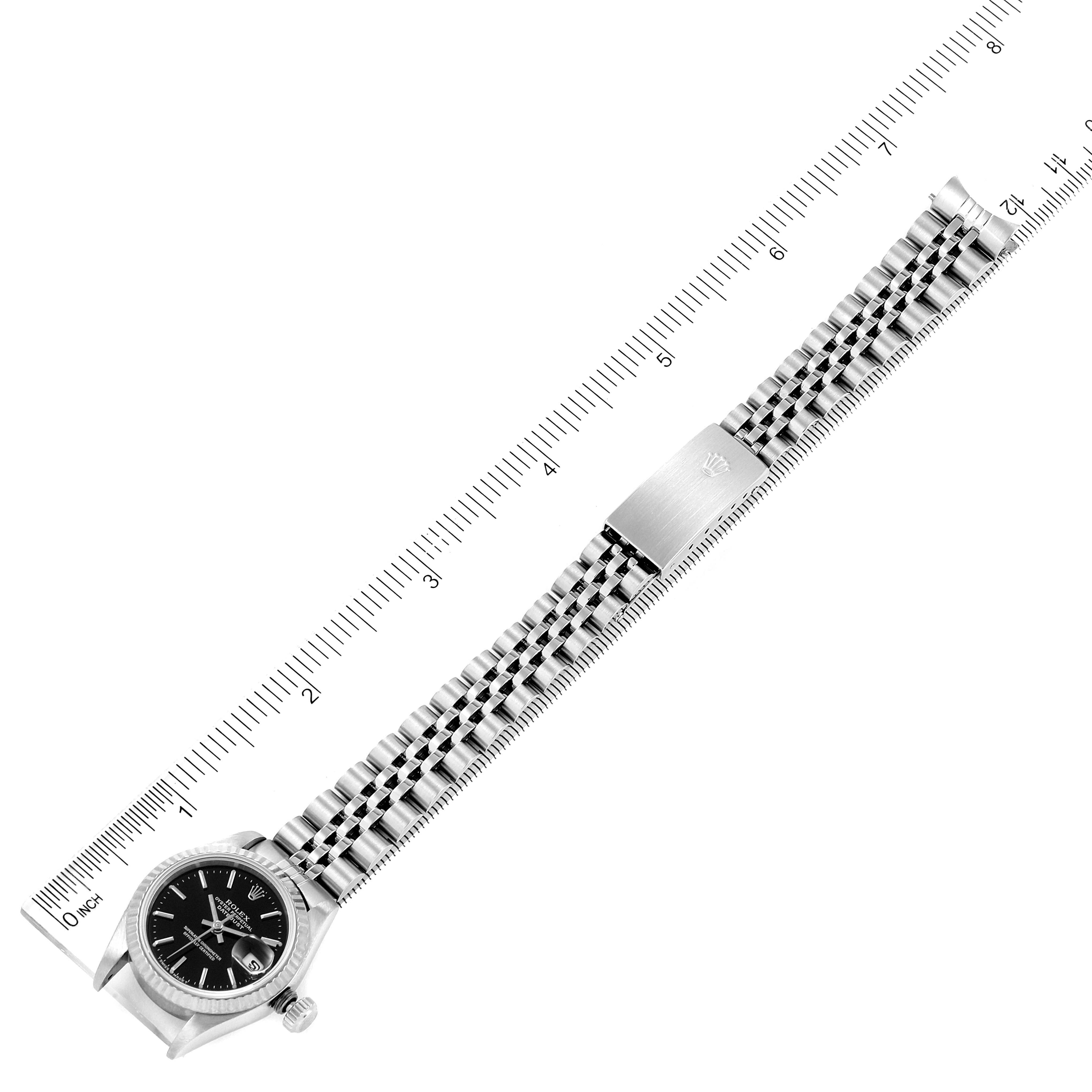 The image shows a Rolex Datejust 69174 Women
s Stainless Steel Black Dial 69174 Women
s Stainless Steel Black Dial watch completely laid flat against a ruler, displaying the whole face and bracelet.