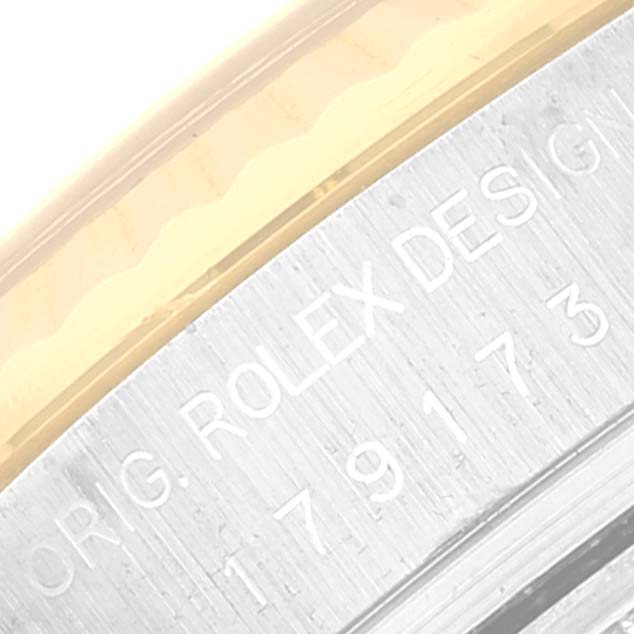 This image shows a close-up of the case side of a Rolex Datejust 179173 Women's Steel and Gold (two tone) Champagne Dial 179173 Women's Steel and Gold (two tone) Champagne Dial watch, featuring engravings and part of the bezel.