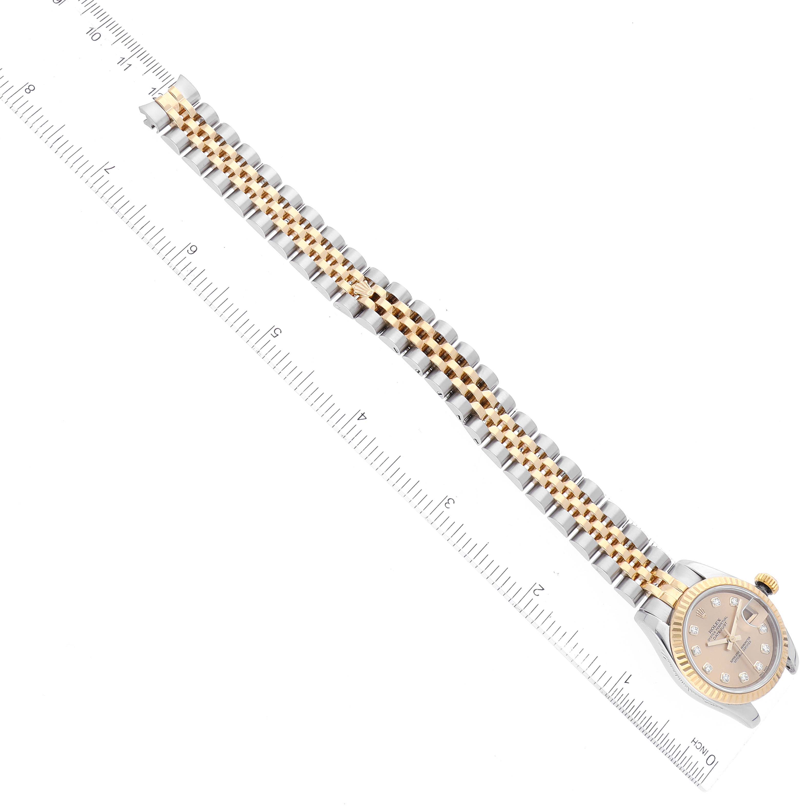 The image shows a top-down view of a Rolex Datejust 179173 Women's Steel and Gold (two tone) Champagne Dial 179173 Women's Steel and Gold (two tone) Champagne Dial watch with its face, crown, and entire bracelet visible next to a ruler.