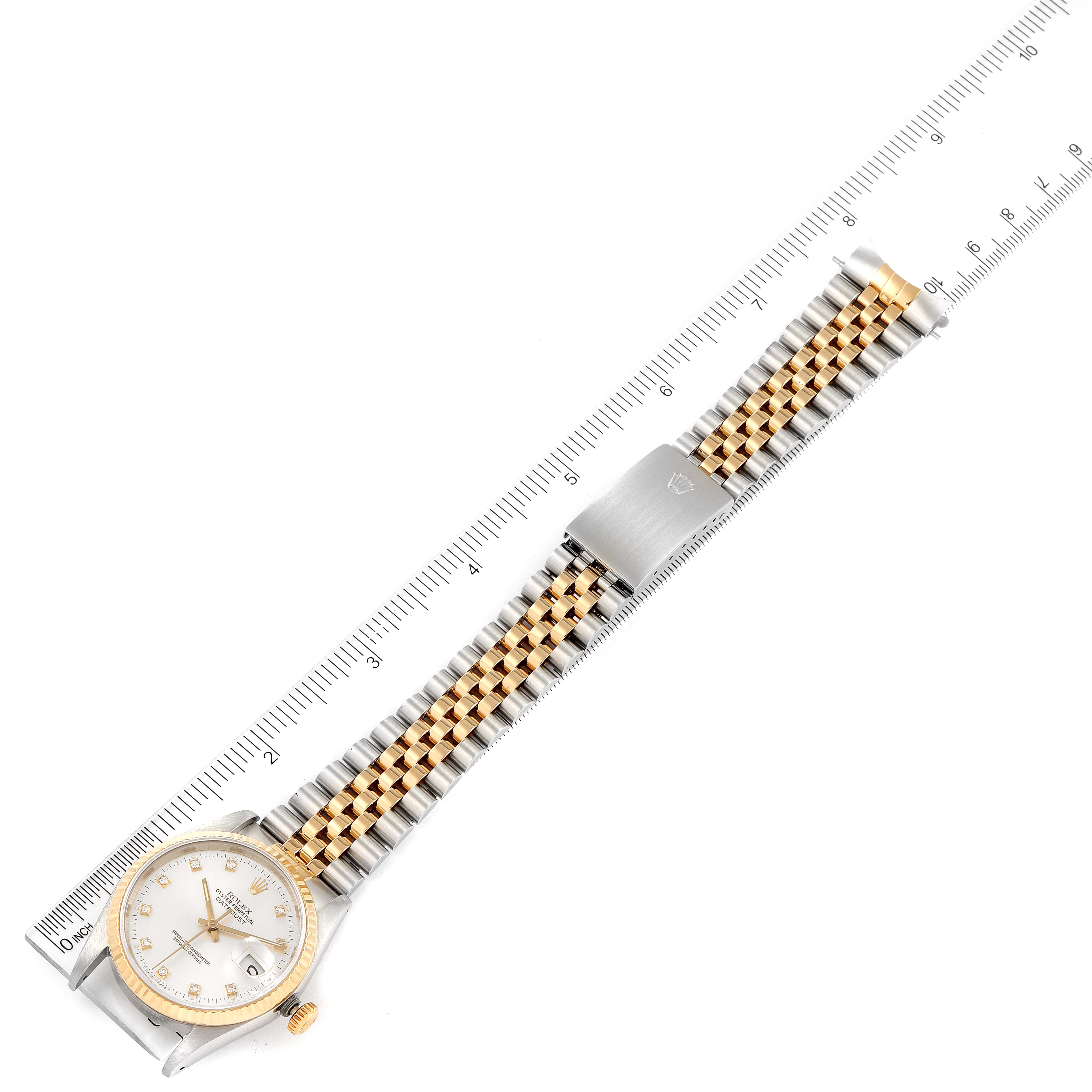 This Rolex Datejust 16233 Men's Steel and Gold (two tone) Silver Dial 16233 Men's Steel and Gold (two tone) Silver Dial watch is shown from a top-down angle, displaying its face, bracelet, and part of its clasp alongside a ruler.