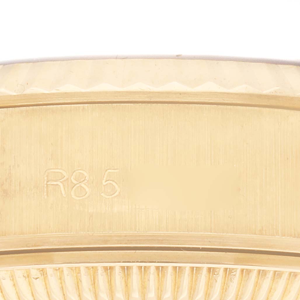 The image shows a close-up of the band and edge of the bezel of a Rolex President 69178 Women
s Yellow Gold Champagne Dial 69178 Women
s Yellow Gold Champagne Dial watch, highlighting its gold texture and serial engraving.