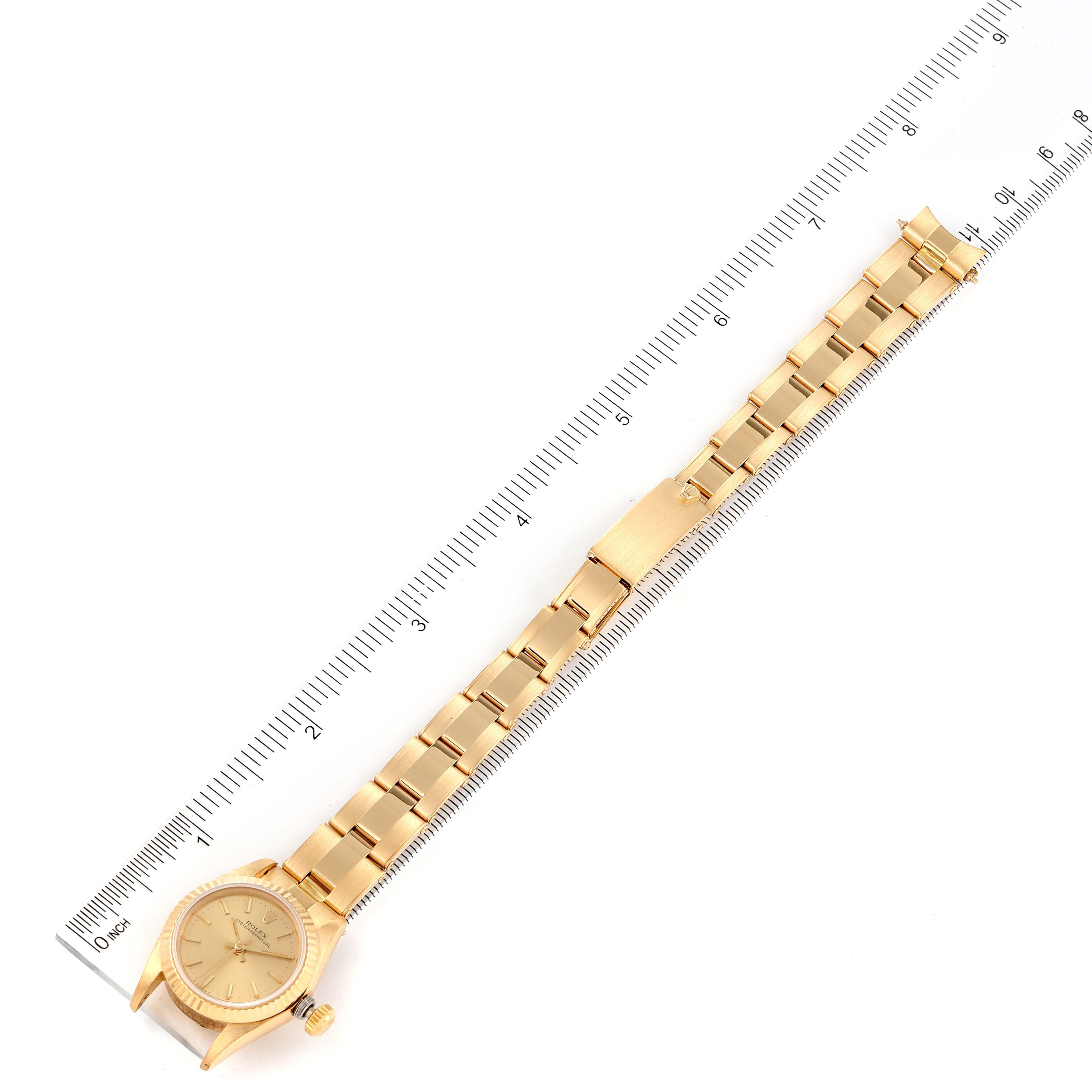 The image shows a Rolex President 67198 Women
s Yellow Gold Champagne Dial 67198 Women
s Yellow Gold Champagne Dial model watch, positioned flat with its full band aligned next to a ruler.