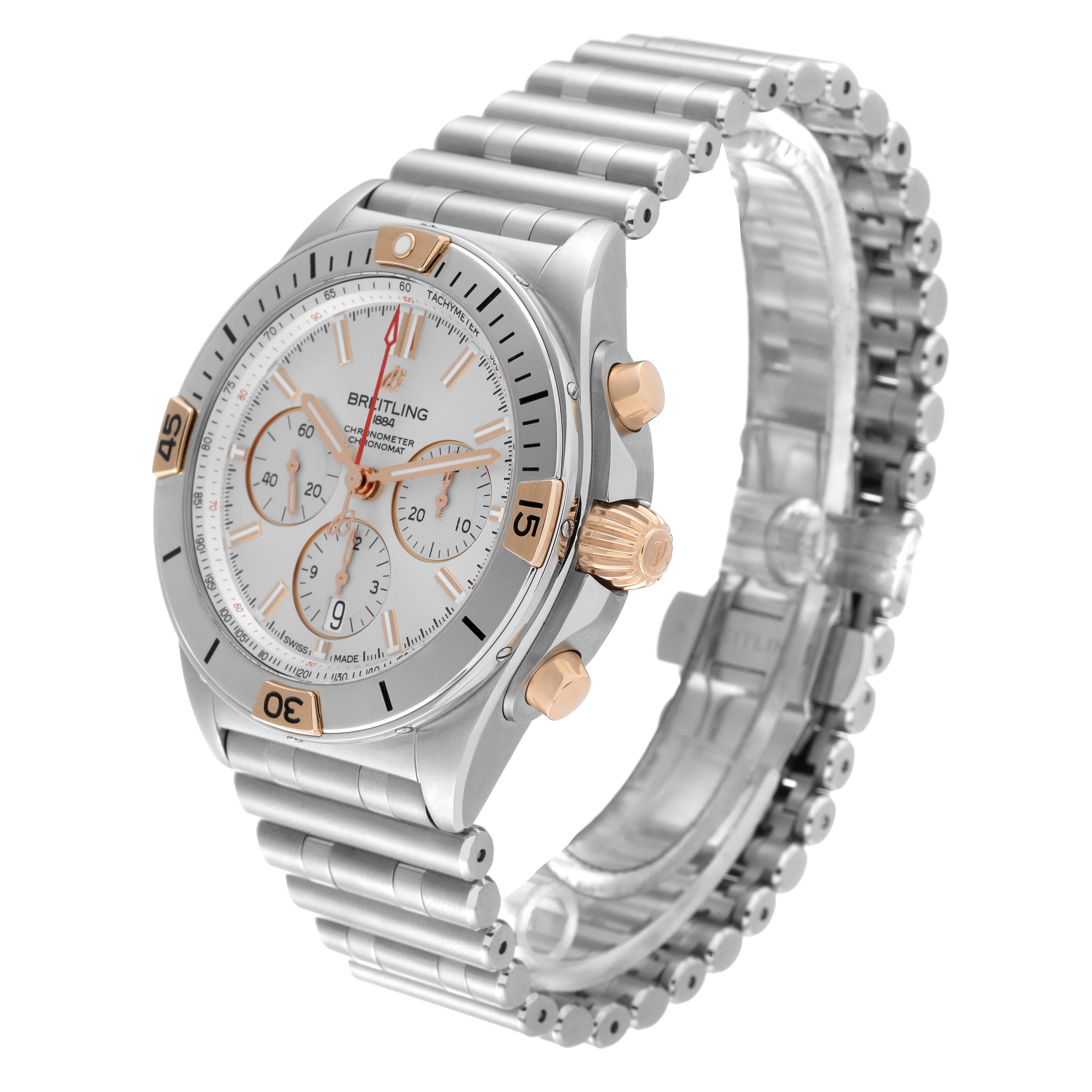 The image shows a Breitling Chronomat IB0134 Men's Steel and Gold (two tone) Silver Dial IB0134 Men's Steel and Gold (two tone) Silver Dial watch at an angle highlighting its face, crown, pushers, and metal bracelet.