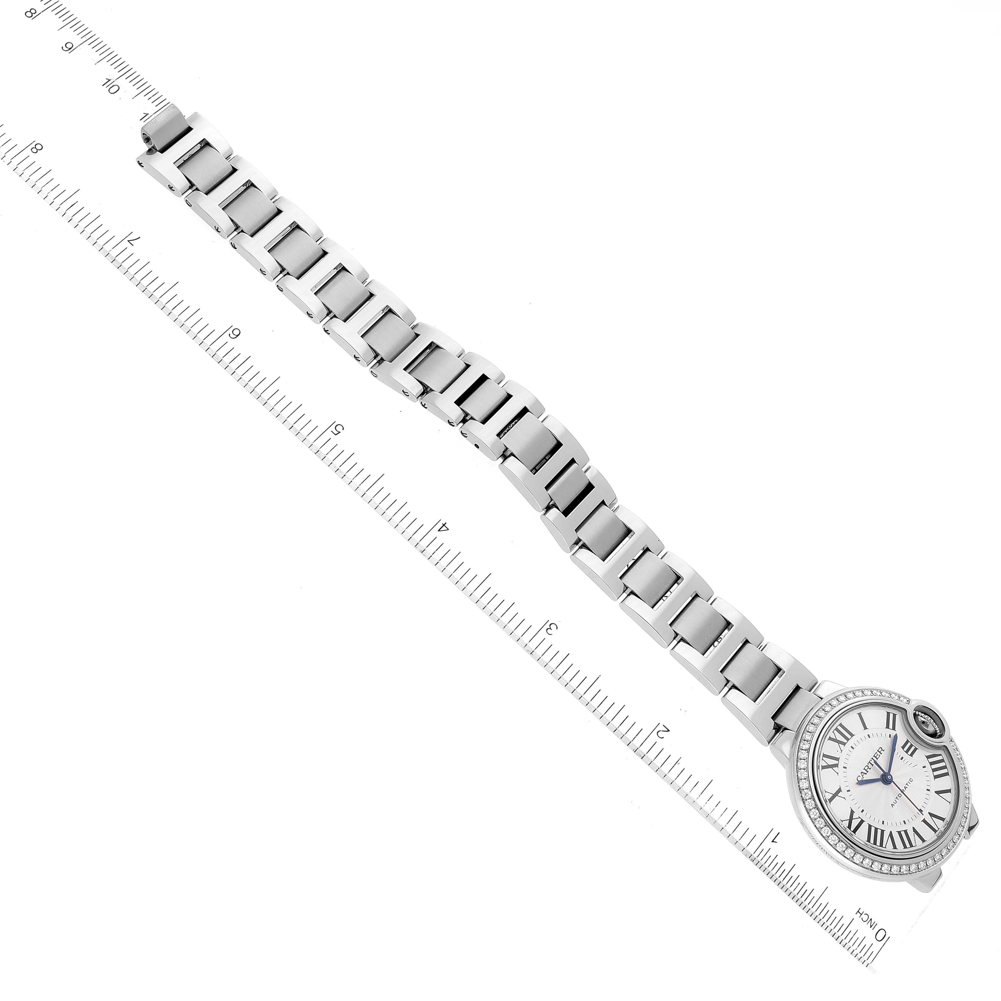 The image shows the Ballon Bleu watch by Cartier laid flat with a focus on the face and bracelet next to a measuring ruler.