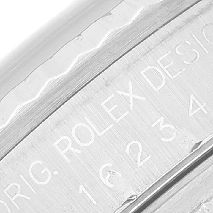 The image shows a close-up view of the engravings on the side of the bezel and case of a Rolex Datejust 16234 Men's Stainless Steel Blue Dial 16234 Men's Stainless Steel Blue Dial watch.