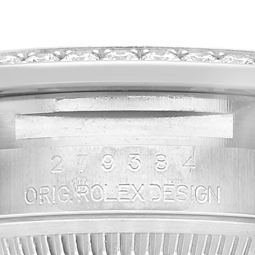 The image shows a close-up of the side of the Rolex Datejust 279384 Women's Stainless Steel Grey Dial 279384 Women's Stainless Steel Grey Dial watch case with engraving "ORIG ROLEX DESIGN" and a partial view of the bezel.