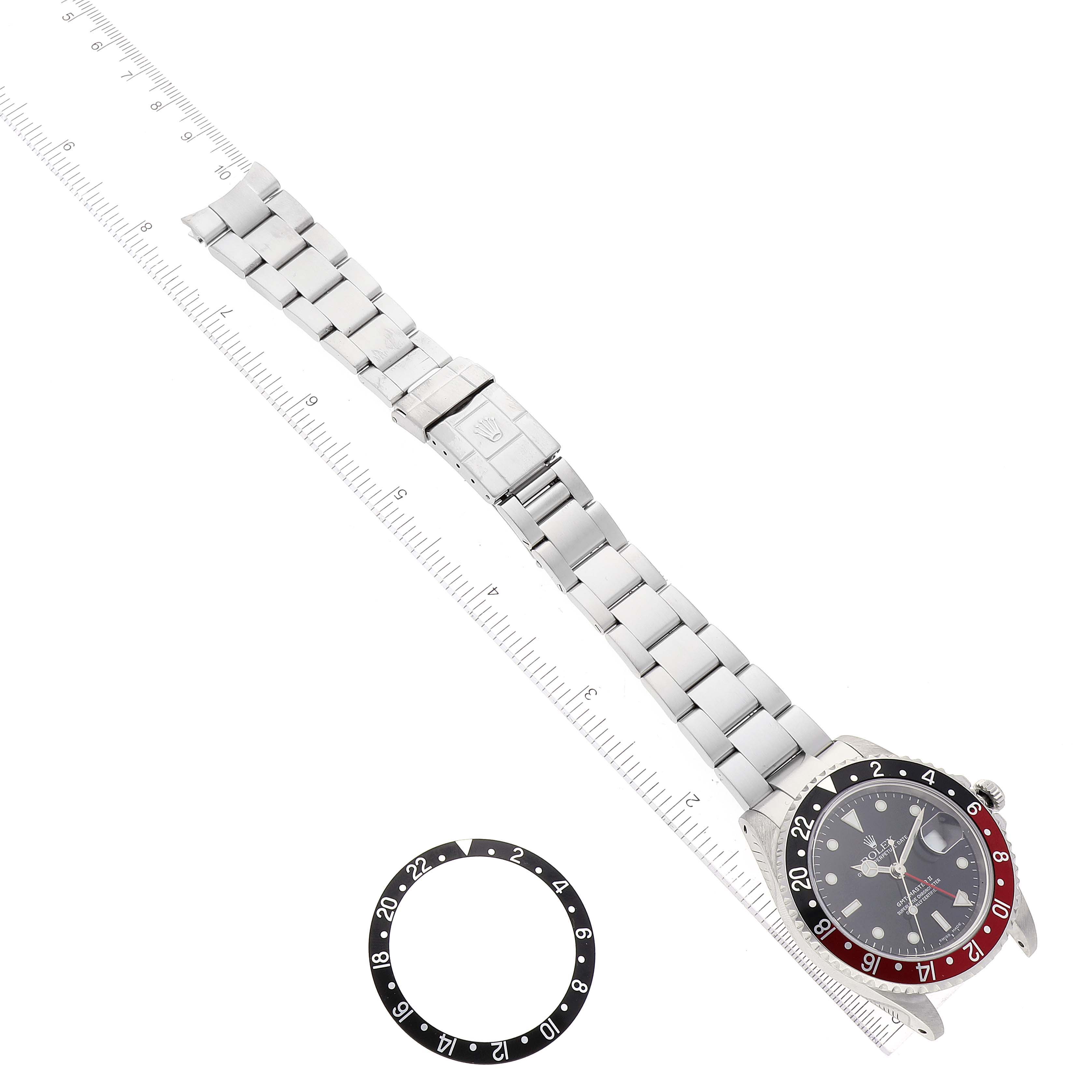 The image shows a top-down view of a Rolex GMT-Master 16710 Men's Stainless Steel Black Dial 16710 Men's Stainless Steel Black Dial watch and a separate bezel with a ruler for scale.