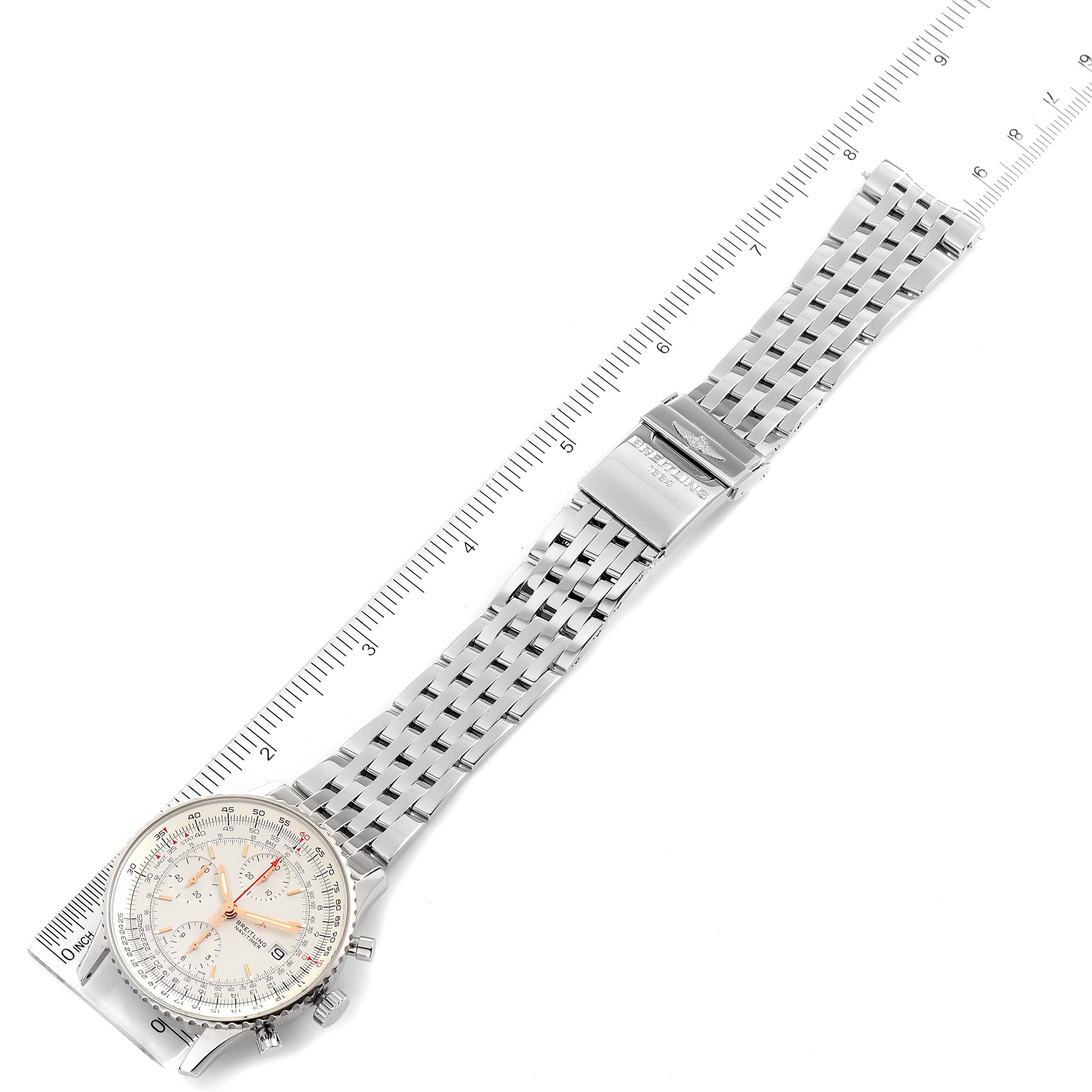 This image shows a full view of the Breitling Navitimer A13324 Men
s Stainless Steel Silver Dial A13324 Men
s Stainless Steel Silver Dial watch, including its face, bracelet, and clasp, next to a measuring ruler.