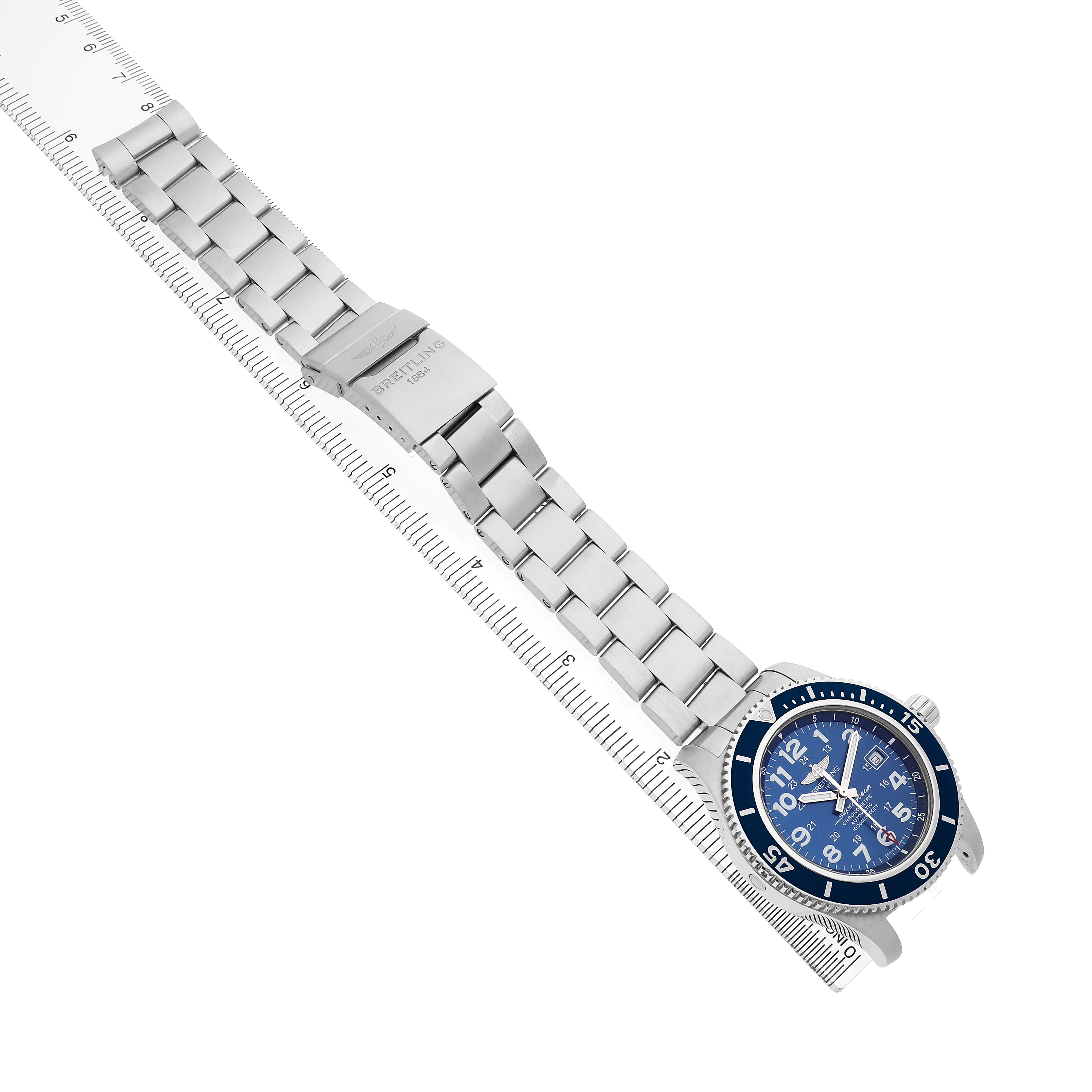The Breitling Superocean A17392 Men's Stainless Steel Blue Dial watch is shown diagonally, displaying its bracelet, clasp, and blue dial with a ruler for scale.