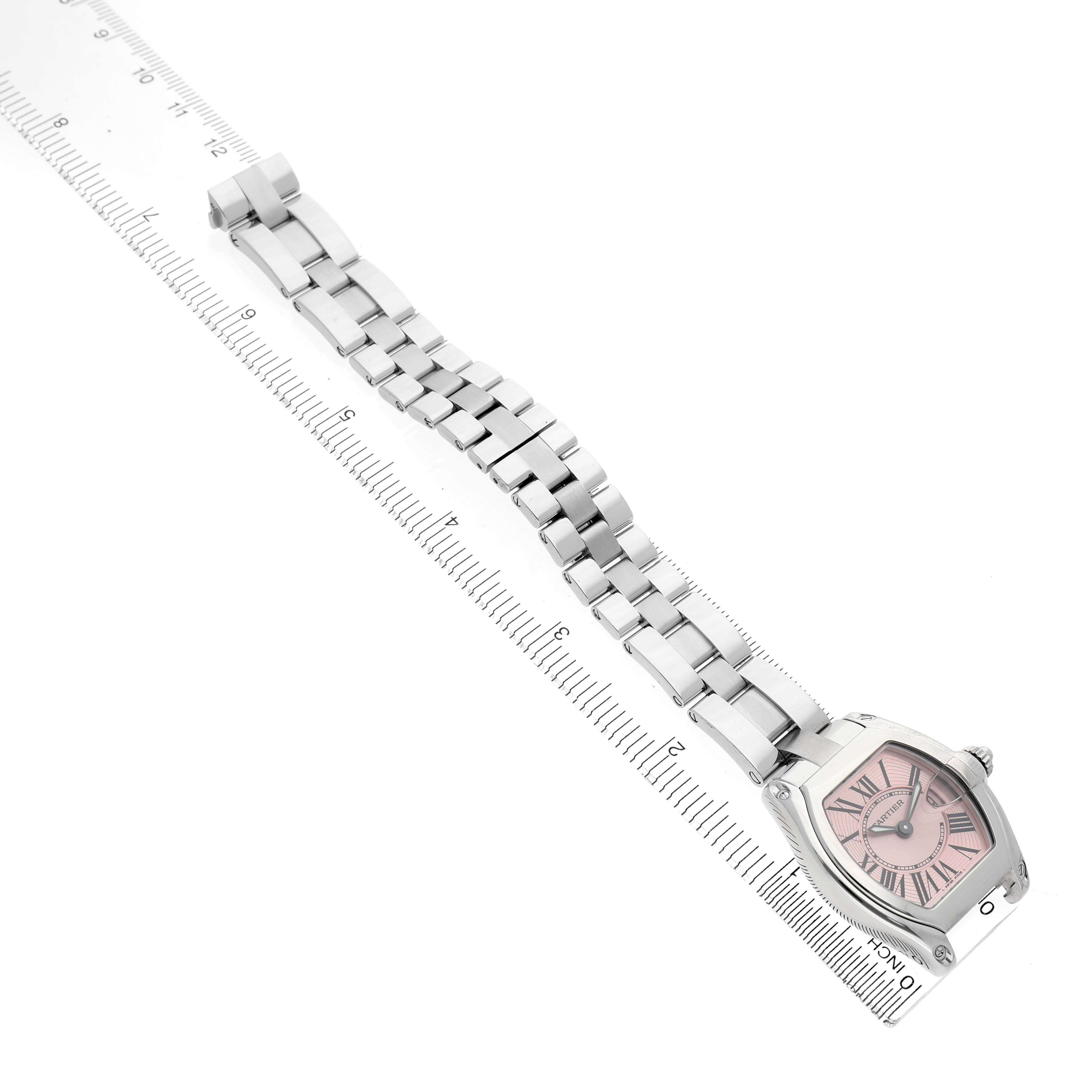 The Cartier Roadster W62017V3 Women's Stainless Steel Pink Dial watch is shown from a top-down angle, displaying its full strap and face beside a ruler for scale.