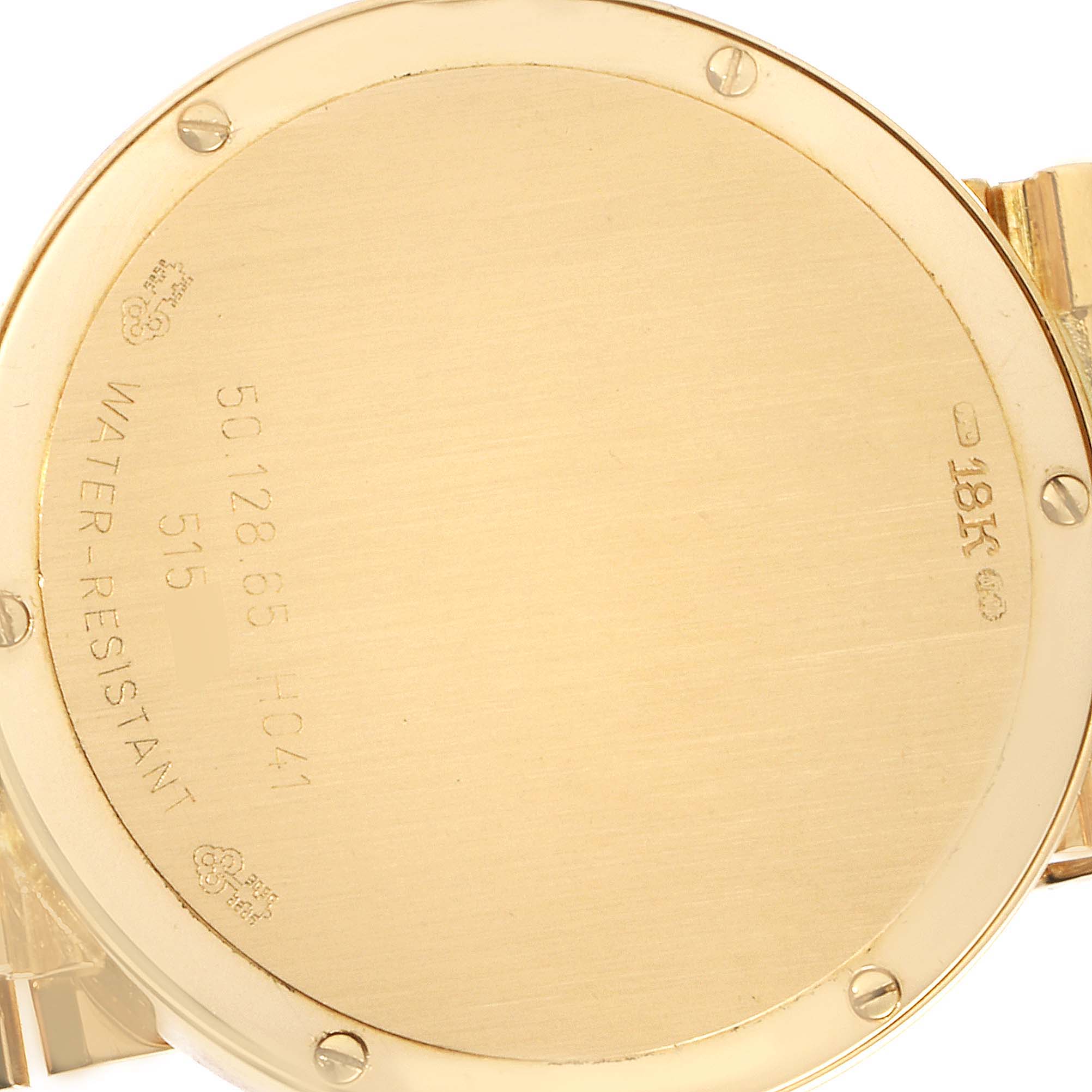 The image shows the case back of the Corum 50.128.65 H-041 Men's Yellow Gold Champagne Dial 50.128.65 H-041 Men's Yellow Gold Champagne Dial 18k Yellow Gold Prism Crystal Diamond Mens Watch 50.128.65, featuring inscriptions and screws.
