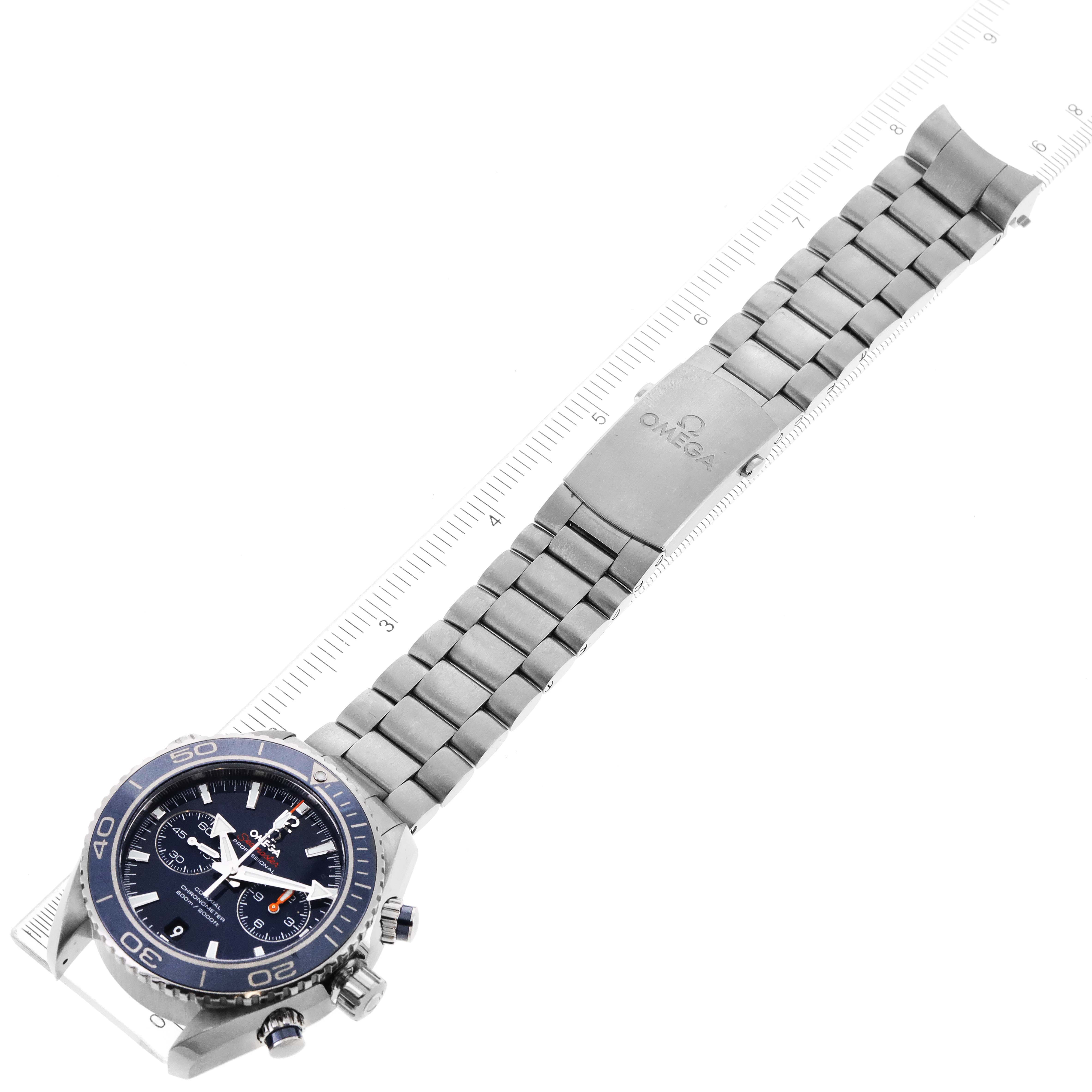 The image shows an Omega Planet Ocean 232.90.46.51.03.001 Men's Titanium Blue Dial 232.90.46.51.03.001 Men's Titanium Blue Dial watch face and metal bracelet laid flat next to a ruler, viewed from an overhead angle.