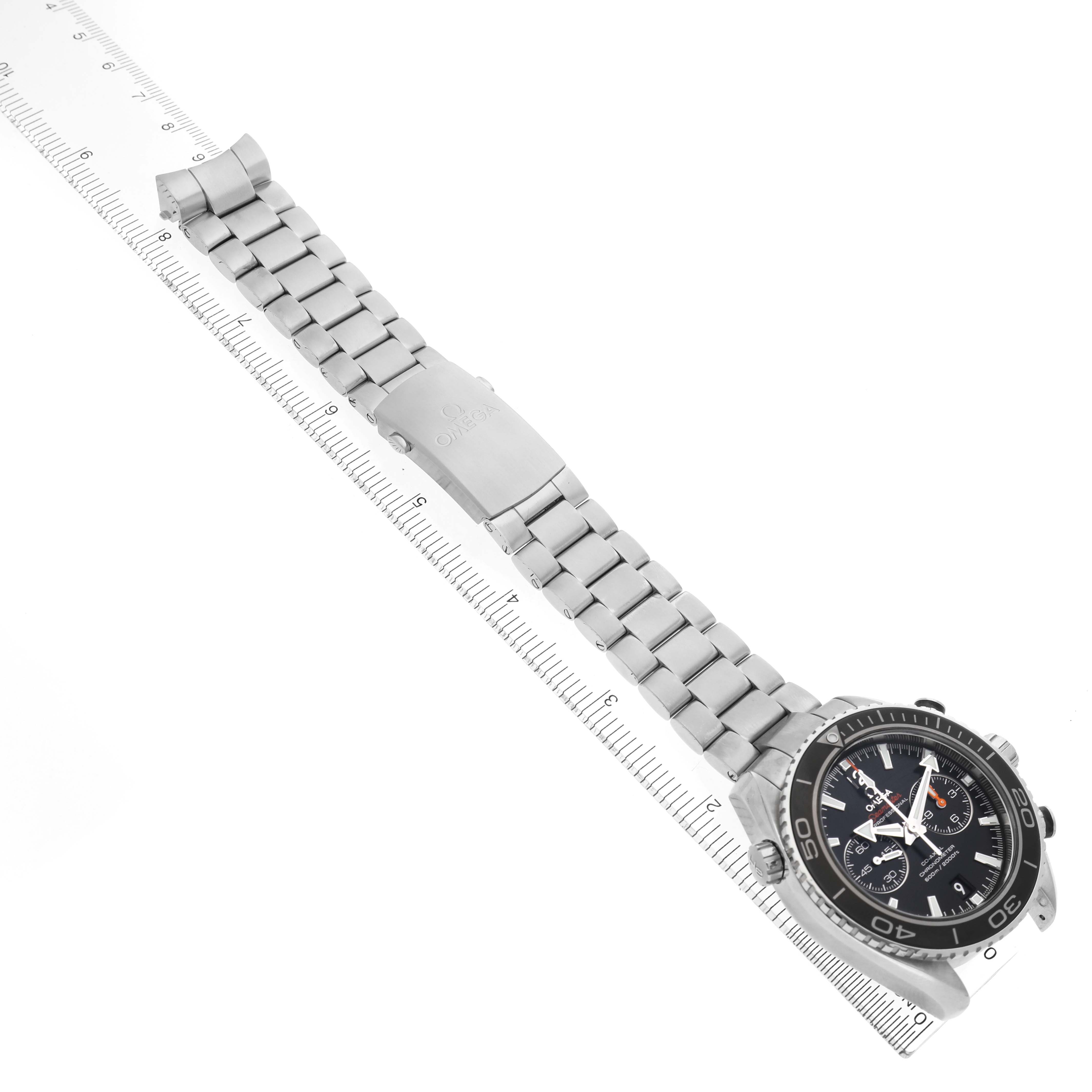 The Omega Seamaster 232.30.46.51.01.003 Men's Stainless Steel Black Dial watch is angled to show the full bracelet and clasp alongside a ruler for size reference.