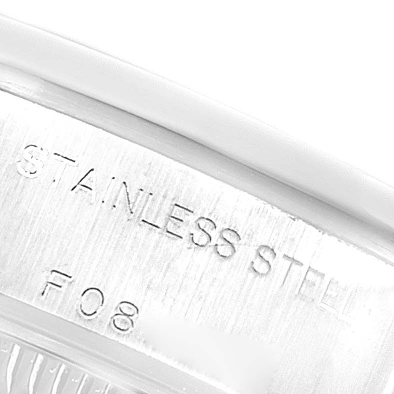 The image shows a close-up of the engraved text "STAINLESS STEEL" on the case of a Rolex Date 79160 Women's Stainless Steel White Dial 79160 Women's Stainless Steel White Dial model watch.