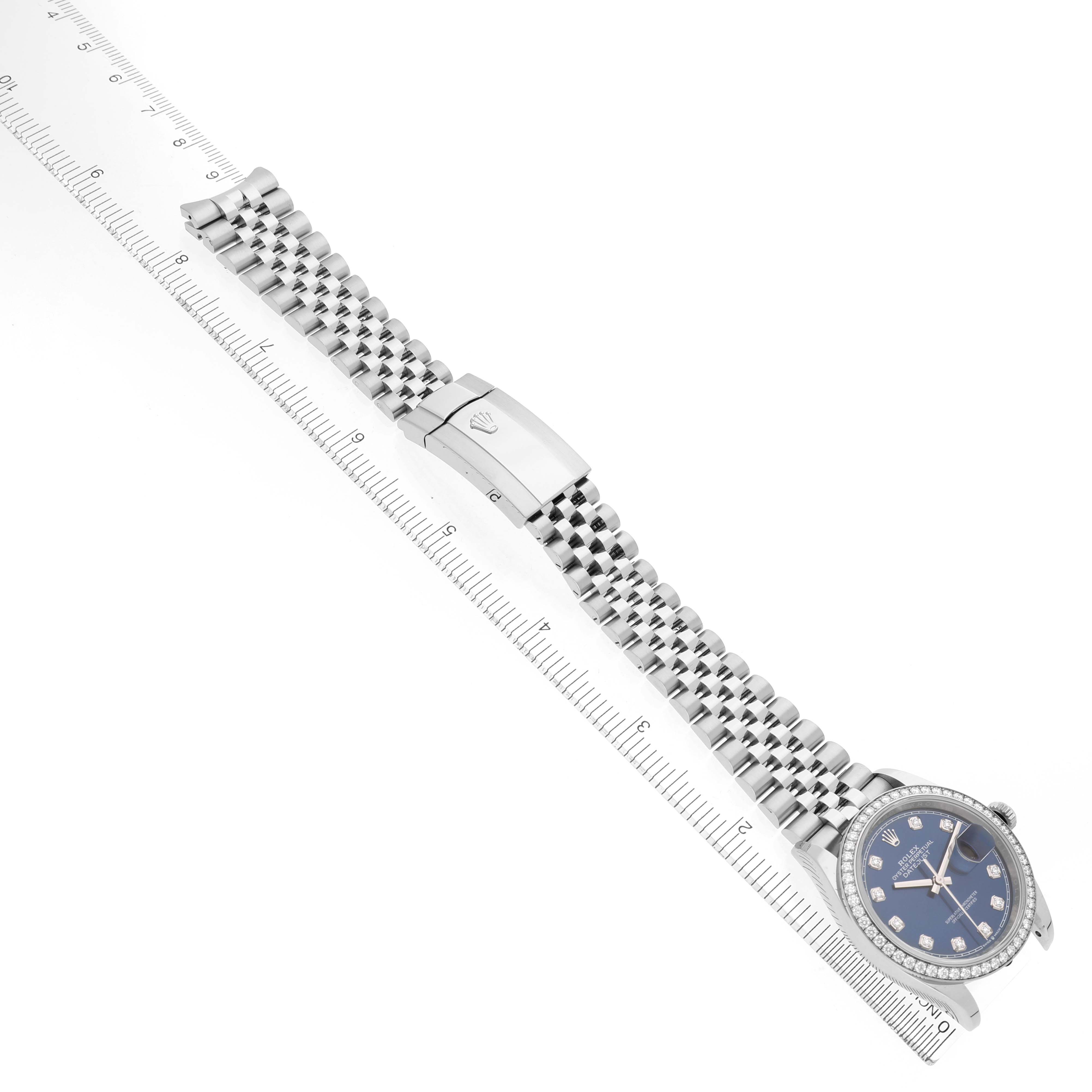 The Rolex Datejust 126284 Men's Stainless Steel Blue Dial watch is shown at an angle, displaying its face, bracelets, and clasp alongside a ruler for scale.